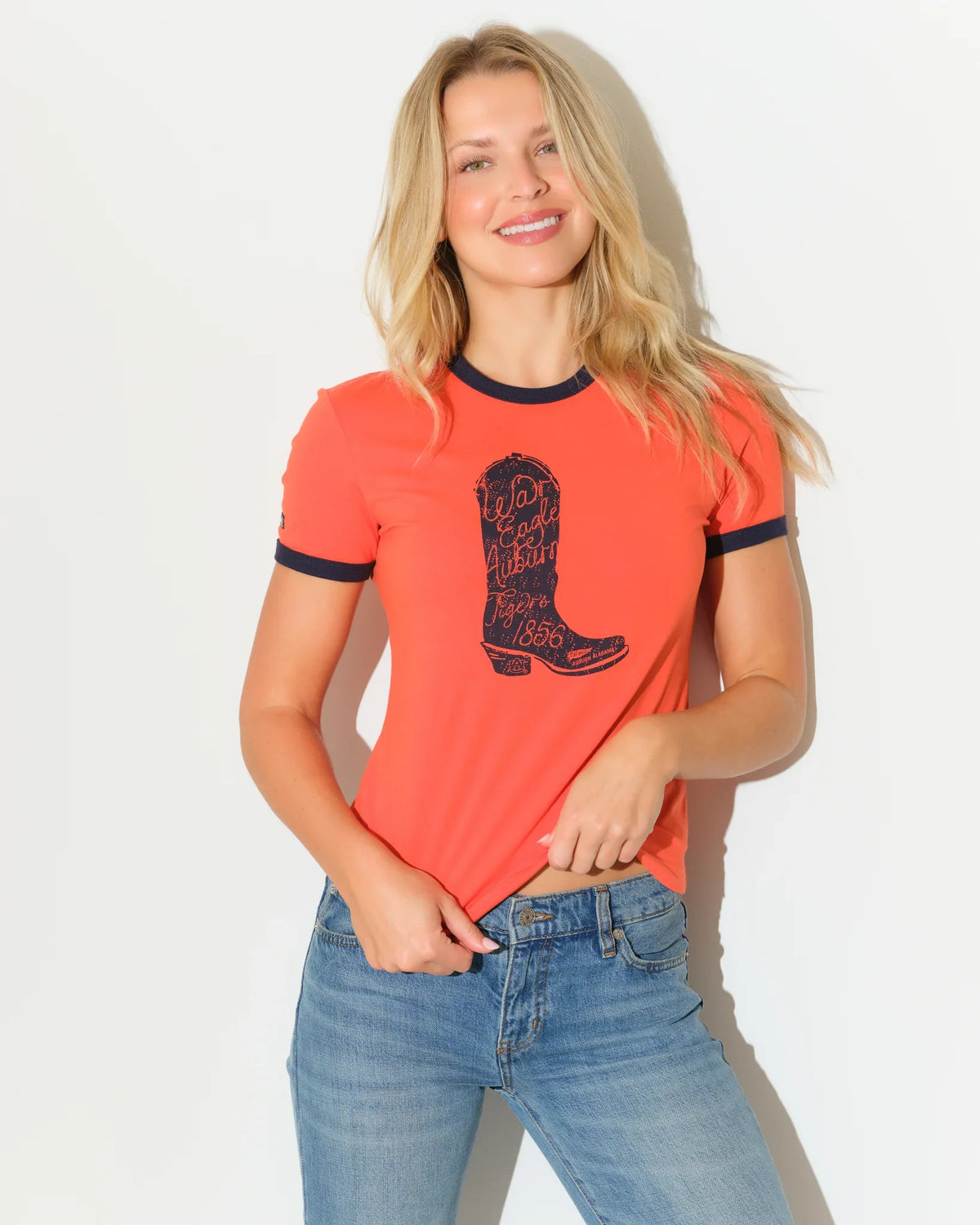 Red Auburn Tigers ringer tee with navy trim and a cowboy boot graphic, styled casually with jeans.