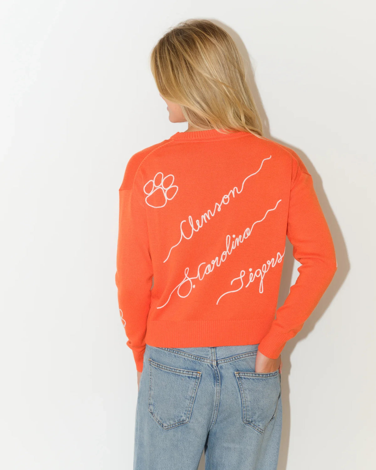 Orange Clemson Tigers Love Letter Sweater with cursive "Clemson," "Carolina," and "Tigers" script lettering and paw print details throughout.