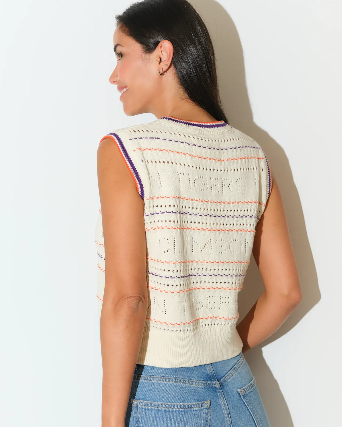 Ivory Clemson Tigers knit sweater vest with embroidered lettering, purple and orange trim at neckline, worn over jeans.