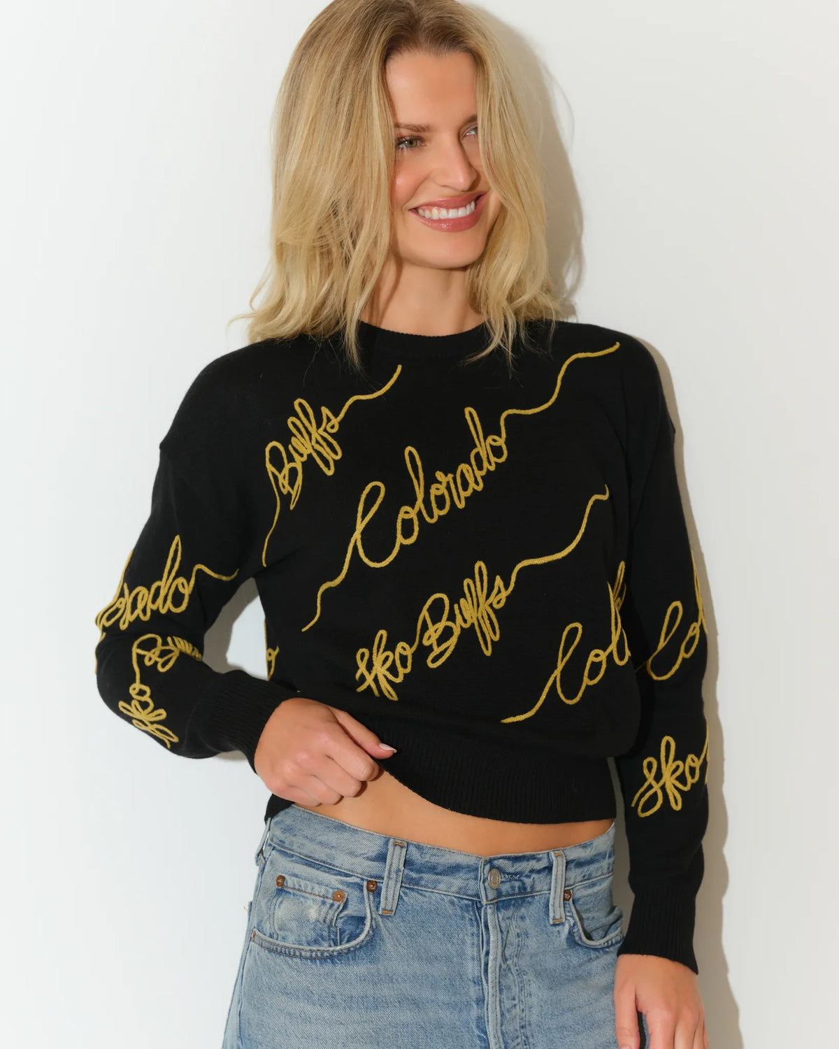 Black Colorado Buffaloes crewneck sweater with gold cursive "Colorado" script repeated across the front and sleeves.