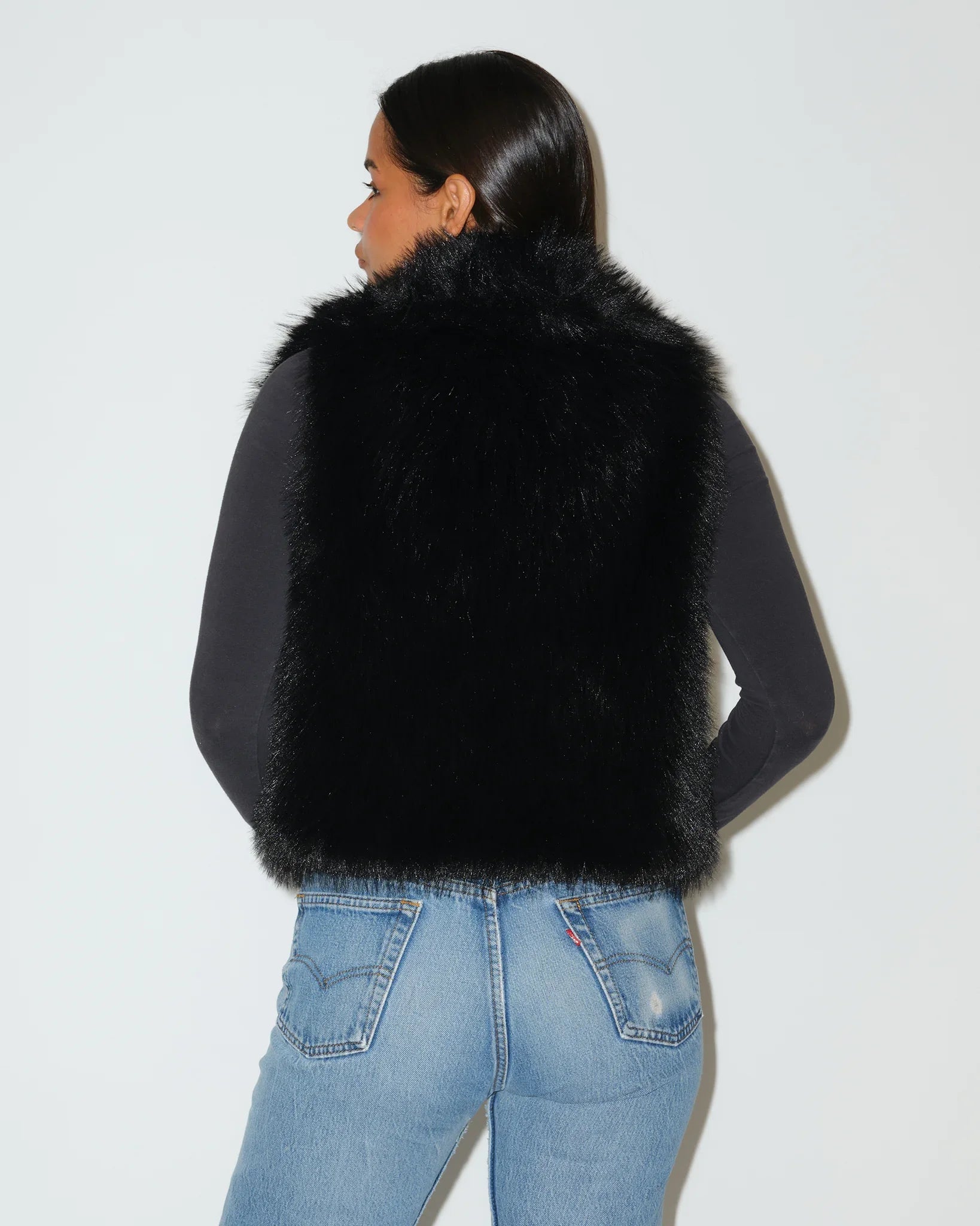 Black Georgia Bulldogs faux fur vest with fluffy texture and open front, styled over a gray long-sleeve top with jeans.