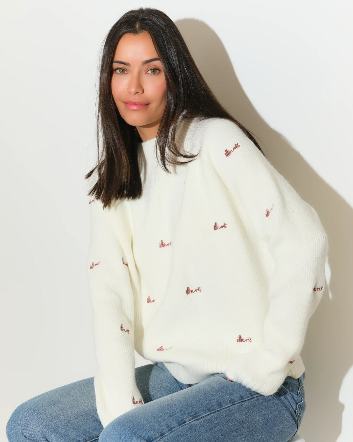 Ivory Illinois Fighting Illini fisherman sweater with allover embroidered script logos, worn with jeans.
