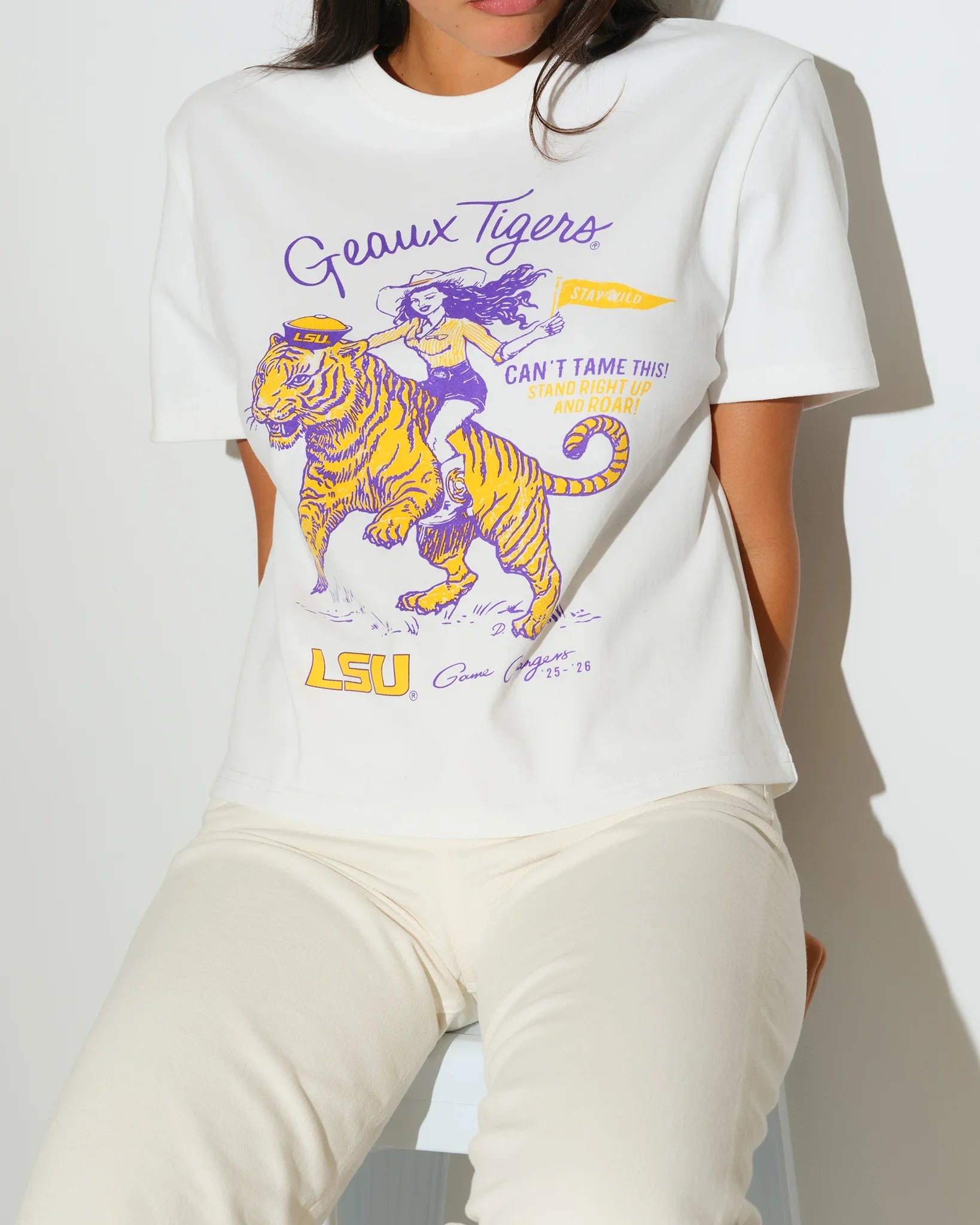 White LSU Tigers Game Changer Tee featuring a graphic of a girl riding a tiger in purple and gold, with "Geaux Tigers" script lettering.