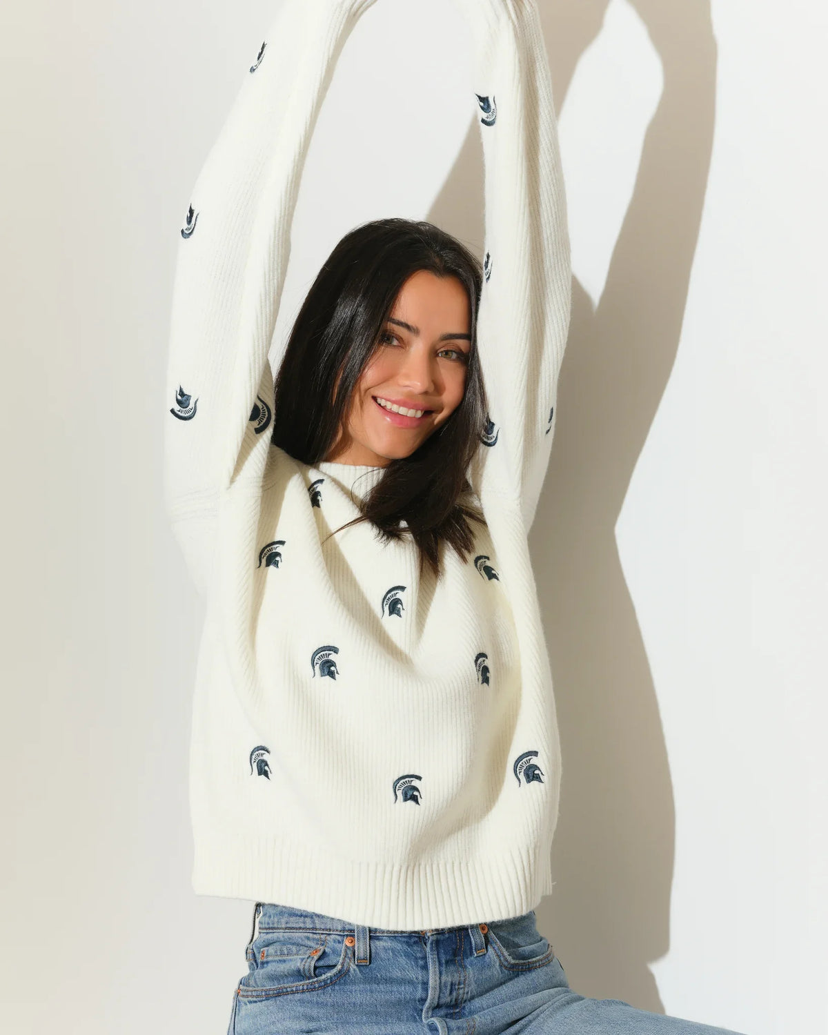 Ivory chunky knit Michigan State Spartans fisherman sweater with allover embroidered Spartan helmet logos, shown with a relaxed crew neck and long sleeves.