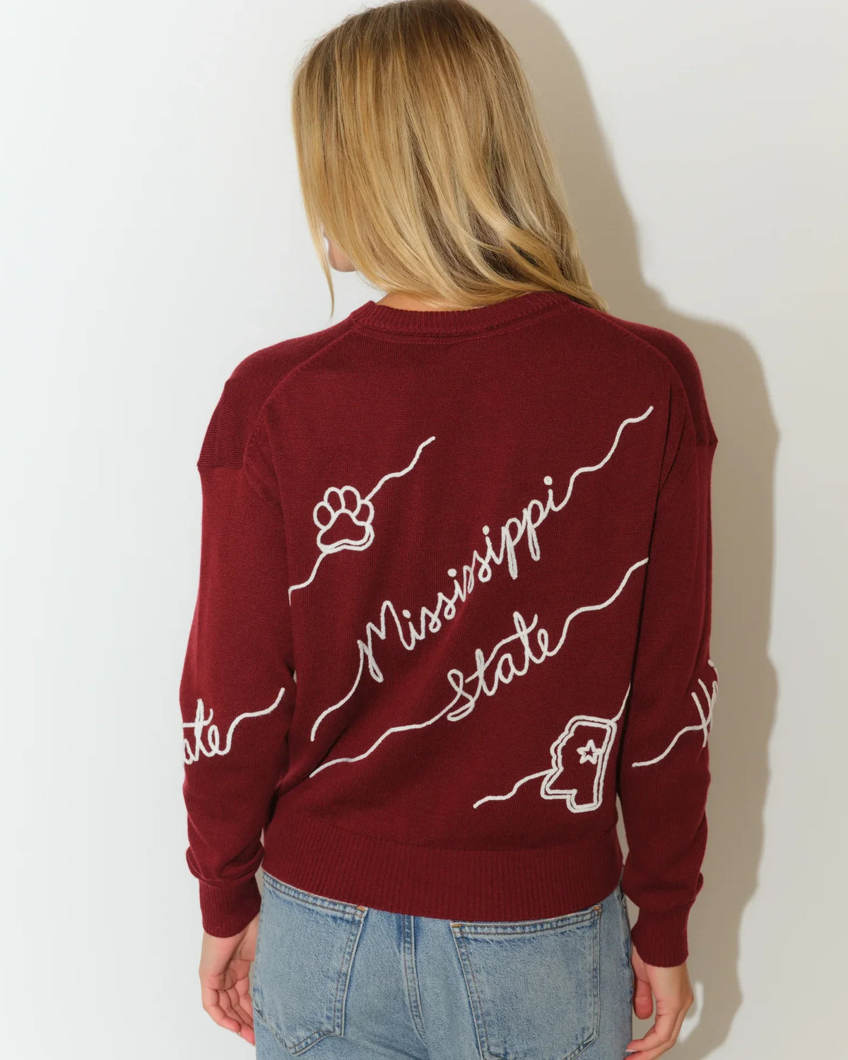 Maroon Mississippi State Bulldogs crew neck sweater with white cursive "Mississippi State" script and decorative wave detailing across the front.