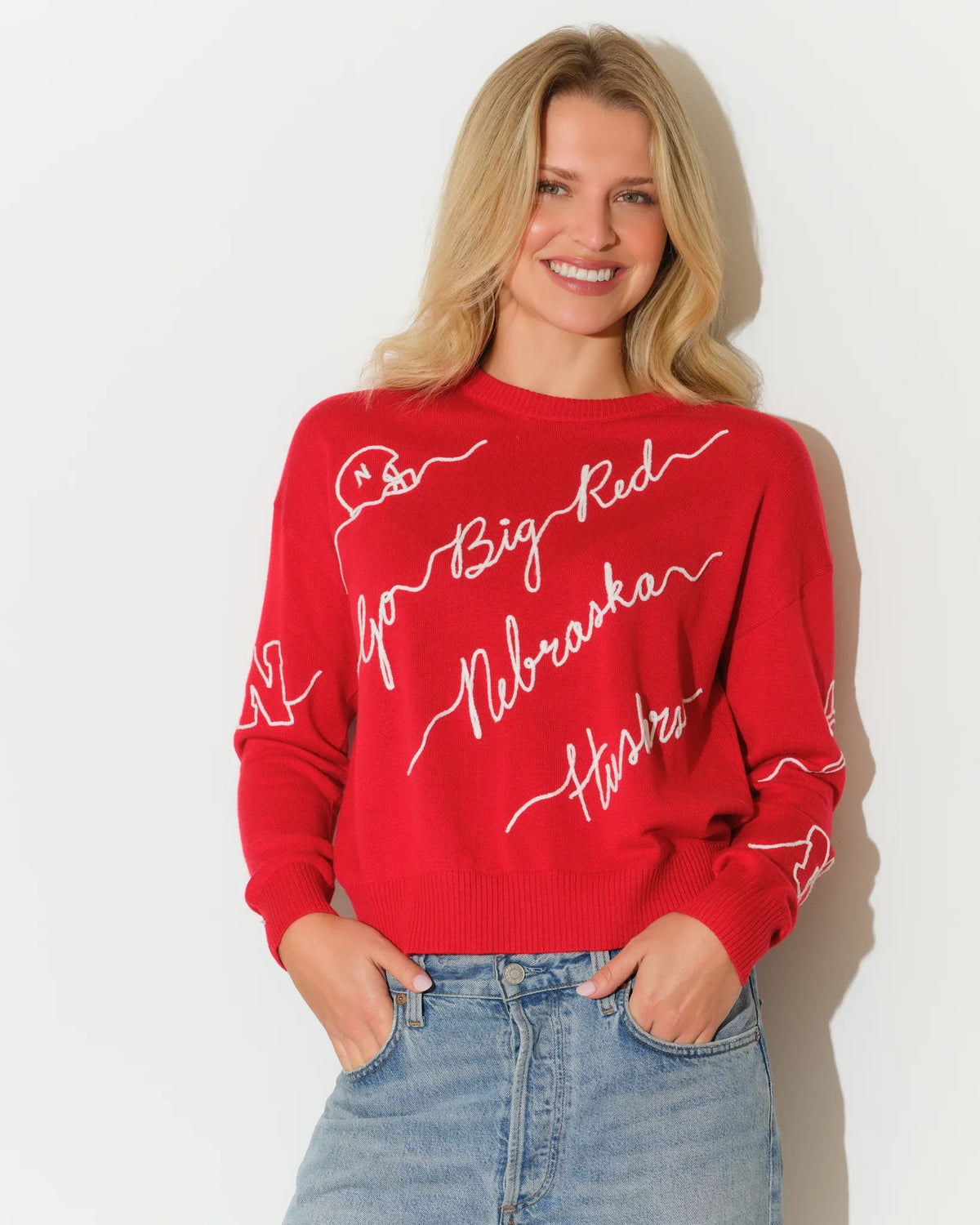 Red Nebraska Cornhuskers women's crewneck sweater with white cursive script reading "Big Red," "Nebraska," and "Huskers" across the front and sleeves.
