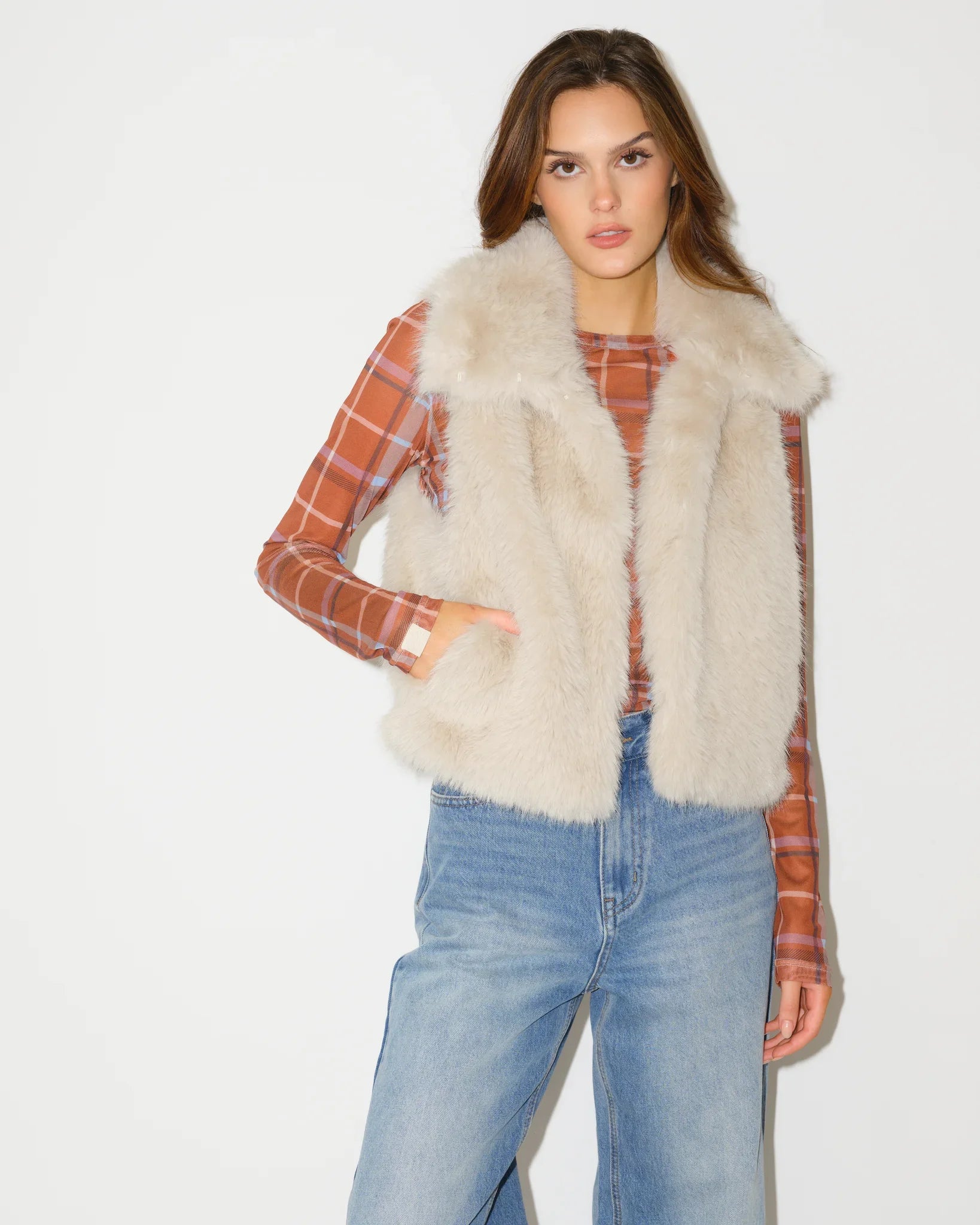 Ivory faux fur Texas Longhorns vest shown open, revealing an orange plaid lining with Longhorns logo print, paired with jeans.