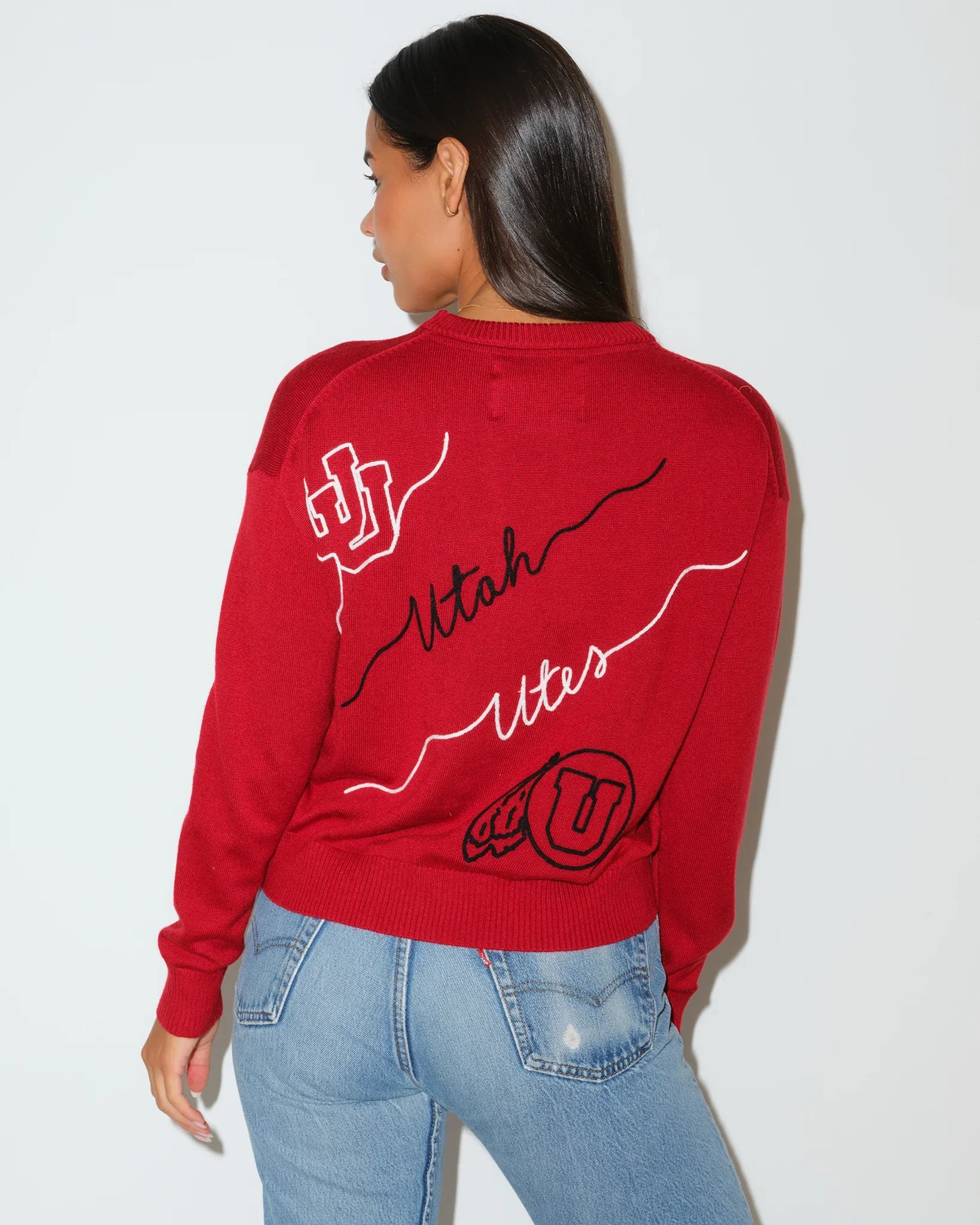 Red Utah Utes crewneck sweater featuring cursive "Utah Utes" script and logo patches on the sleeves and chest.