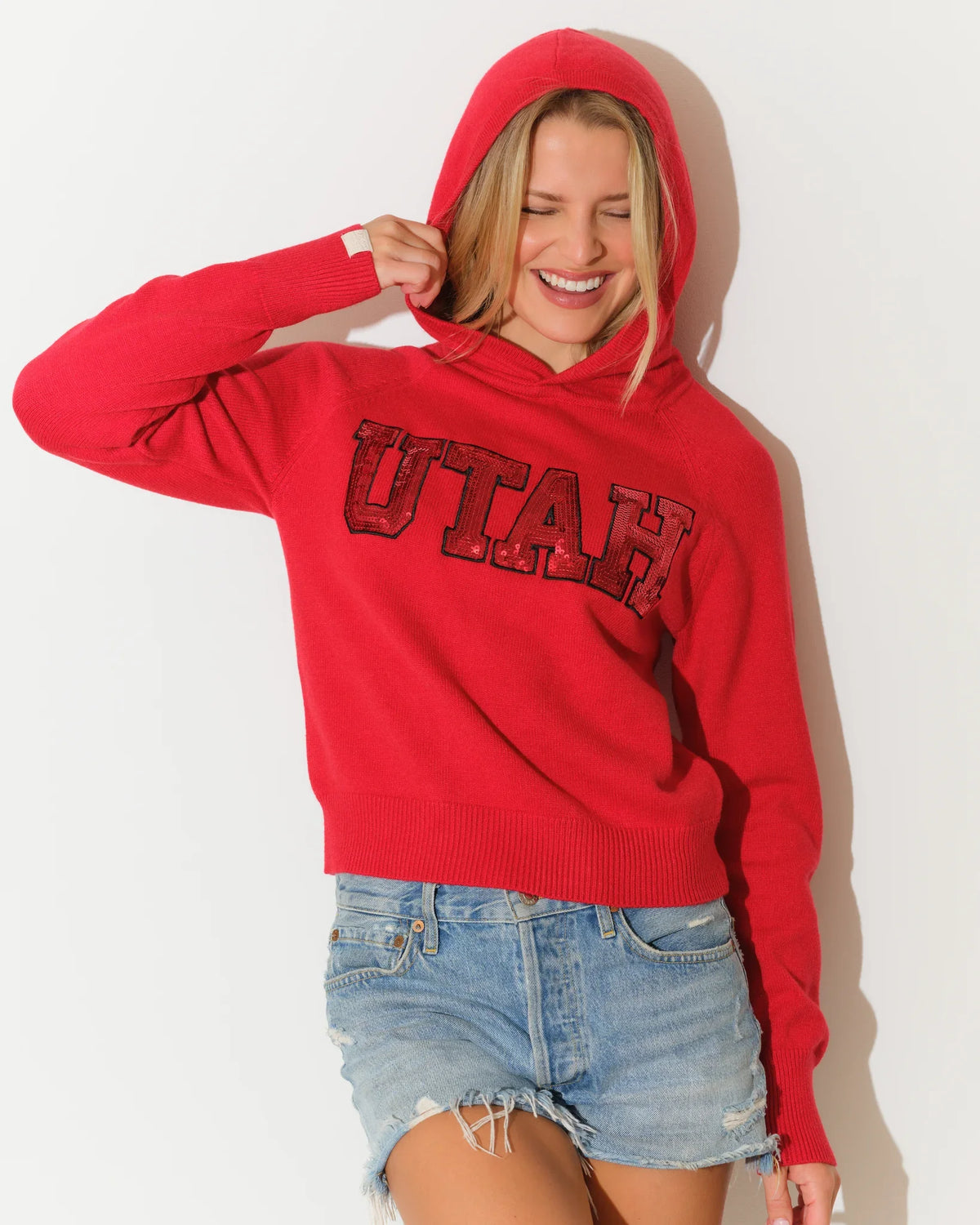 Red Utah Utes women's cropped pullover hoodie featuring sequin block letter "UTAH" graphic across the chest.