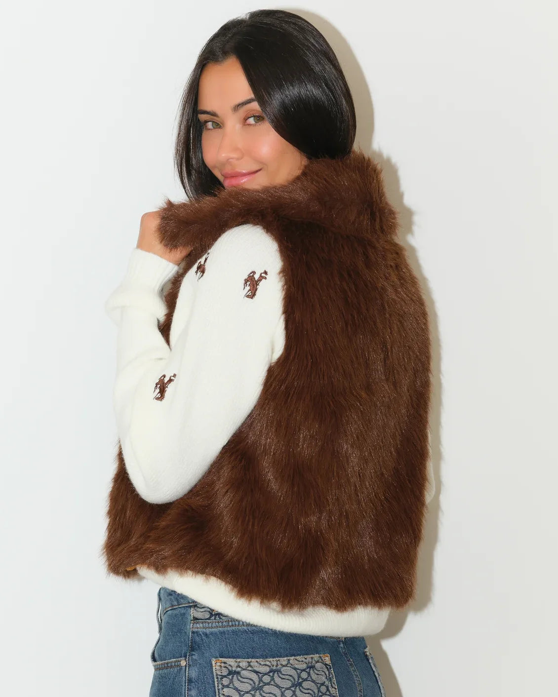 Brown faux fur Wyoming Cowboys vest with gold printed lining, shown open over a white Cowboys-embroidered sweater.