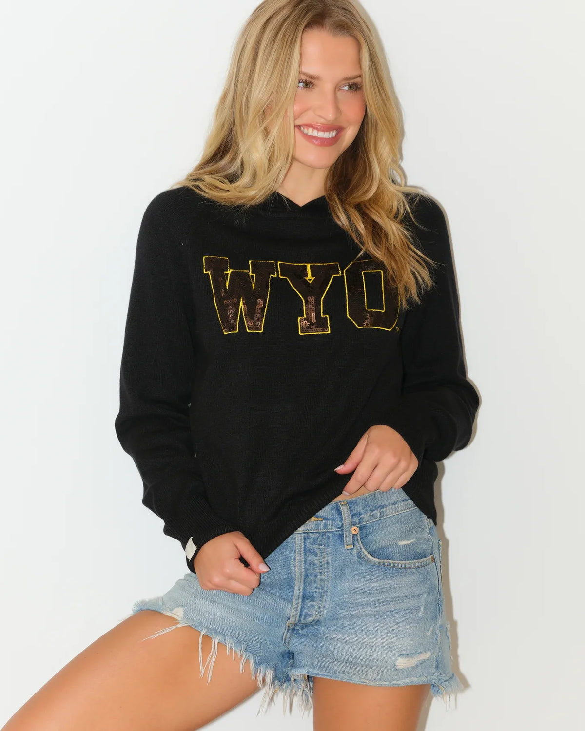 Black Wyoming Cowboys sequin knit hoodie featuring gold sequin "WYO" lettering on the chest, modeled with a relaxed fit.