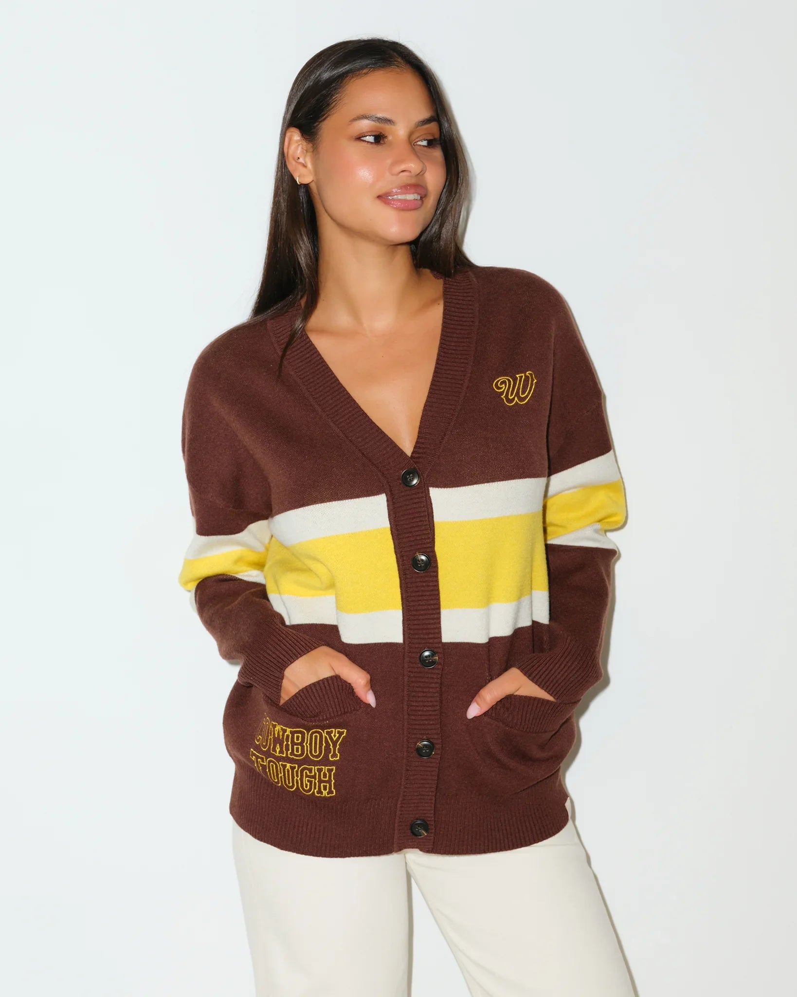 Brown Wyoming Cowboys oversized cardigan with yellow and white chest stripes, gold embroidered logo, and "Wyoming Cowboys" text on the hem.