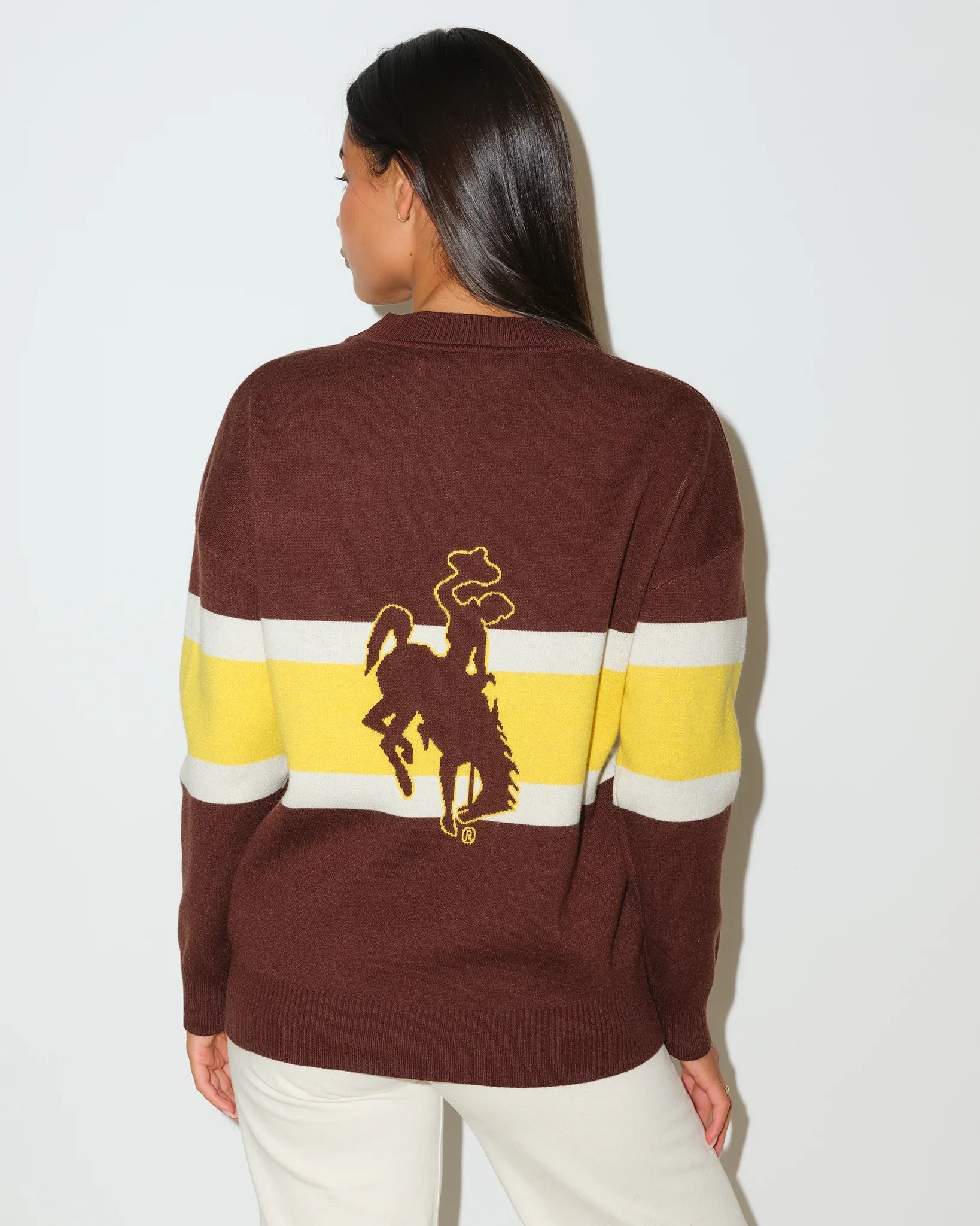 Brown Wyoming Cowboys oversized cardigan with yellow and white chest stripes, gold embroidered logo, and "Wyoming Cowboys" text on the hem.