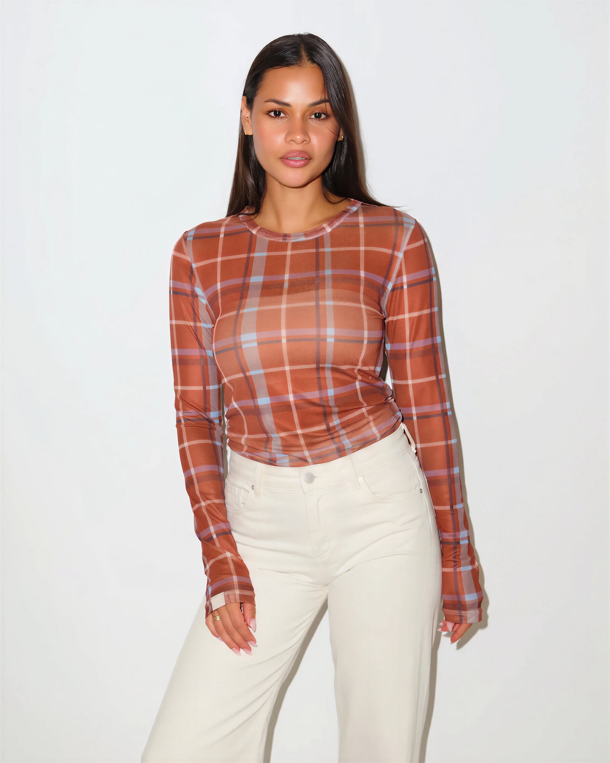 woman wearing a sheet plaid top that is a burnt orange color. It is long sleeve.