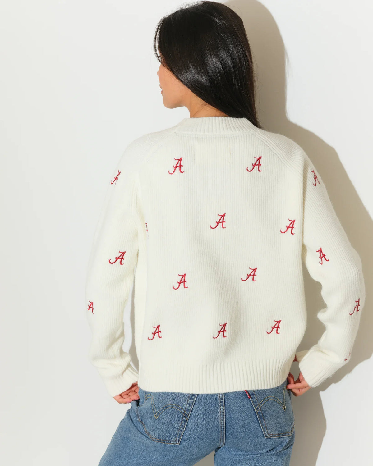 Ivory Alabama Crimson Tide fisherman sweater featuring an allover red "A" logo pattern, shown with a relaxed crewneck fit.
