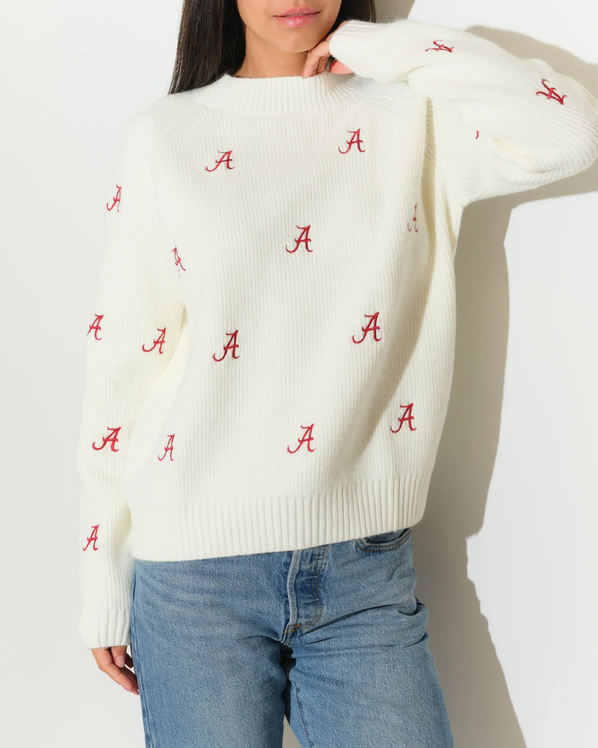 Ivory Alabama Crimson Tide fisherman sweater featuring an allover red "A" logo pattern, shown with a relaxed crewneck fit.