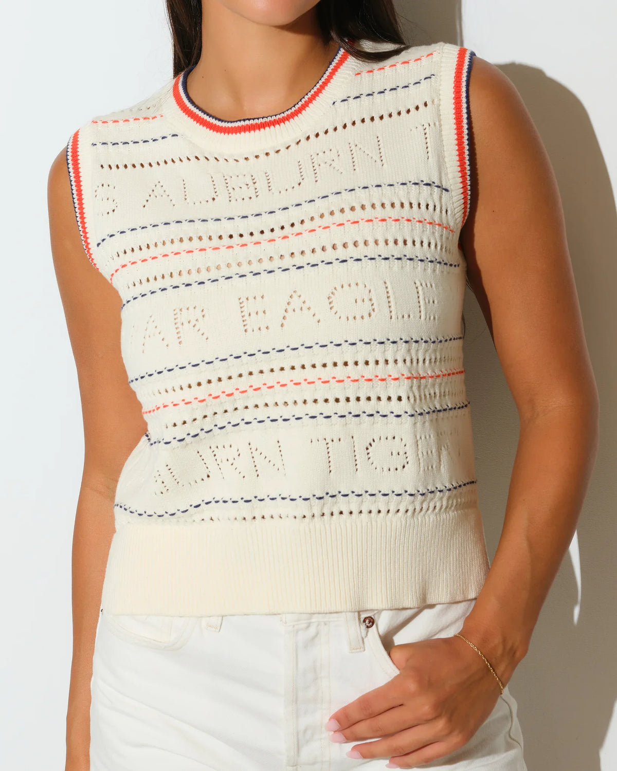 Ivory Auburn Tigers open-knit sweater vest with red trim detailing at the neckline, shown styled with white denim shorts.