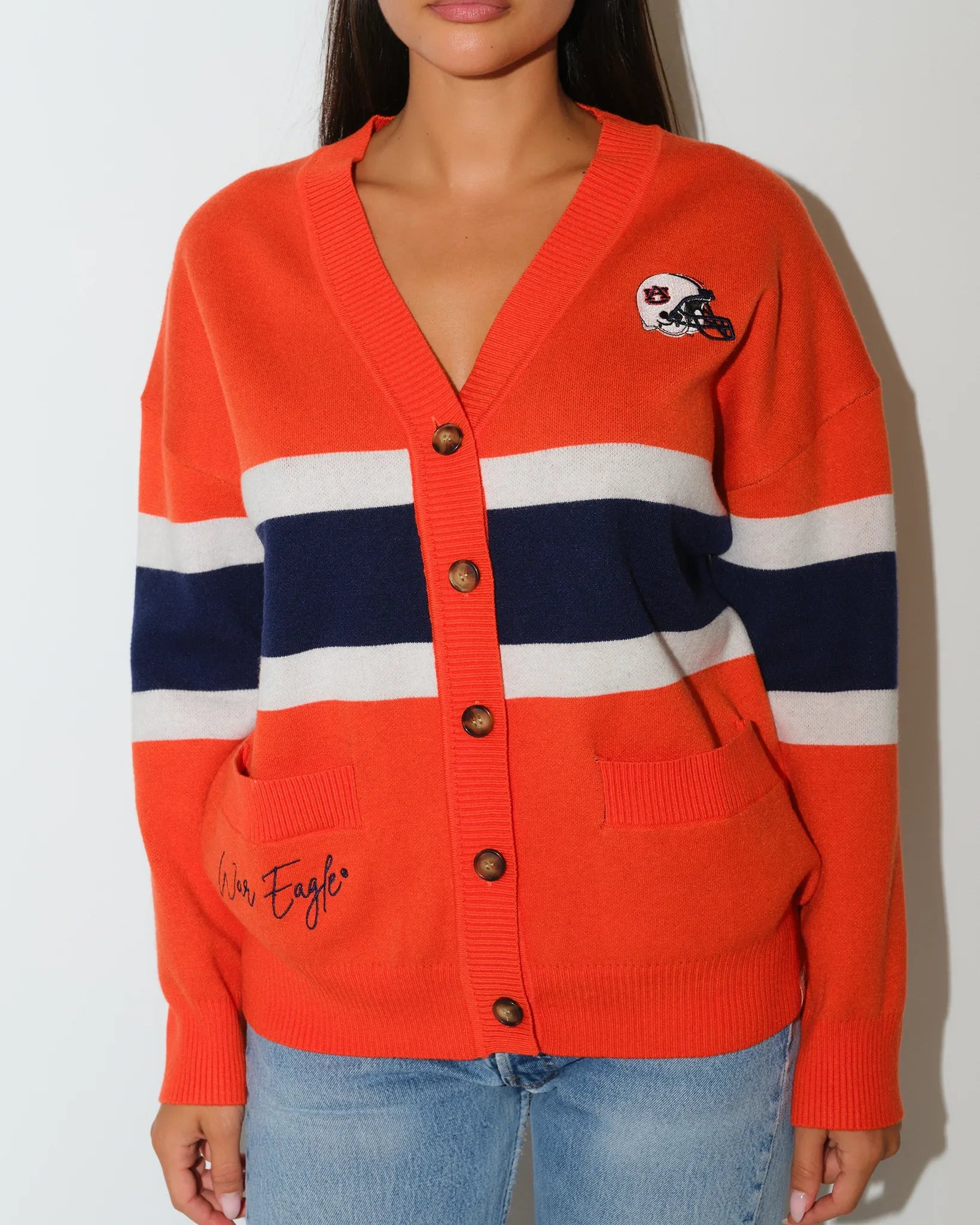 Orange Auburn Tigers Vinti cardigan with navy and white chest stripes, button front, and embroidered logo patch, styled with jeans.