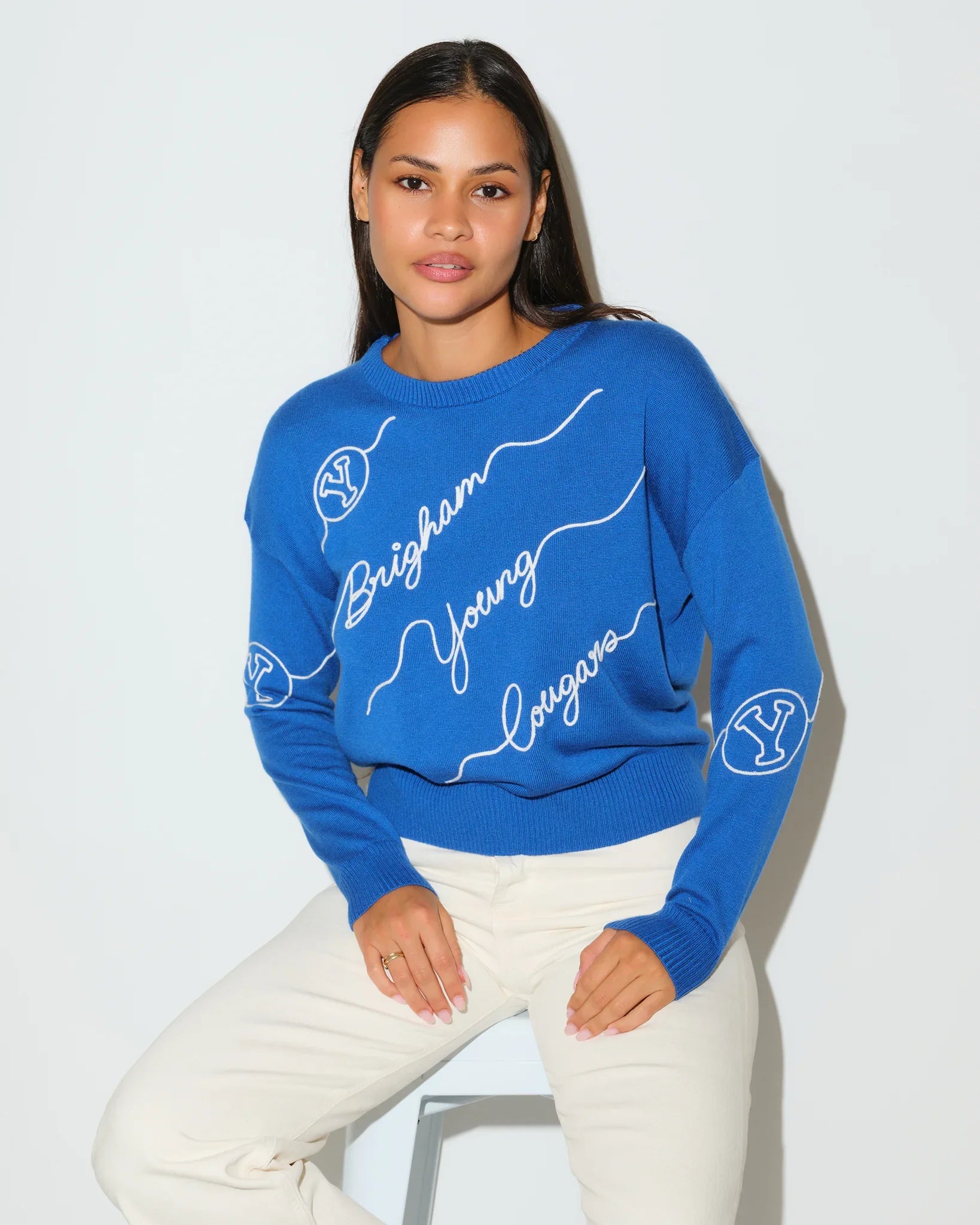 Royal blue BYU Cougars crewneck sweater featuring cursive "Brigham Young" script lettering across the front with a small BYU logo on the sleeve.