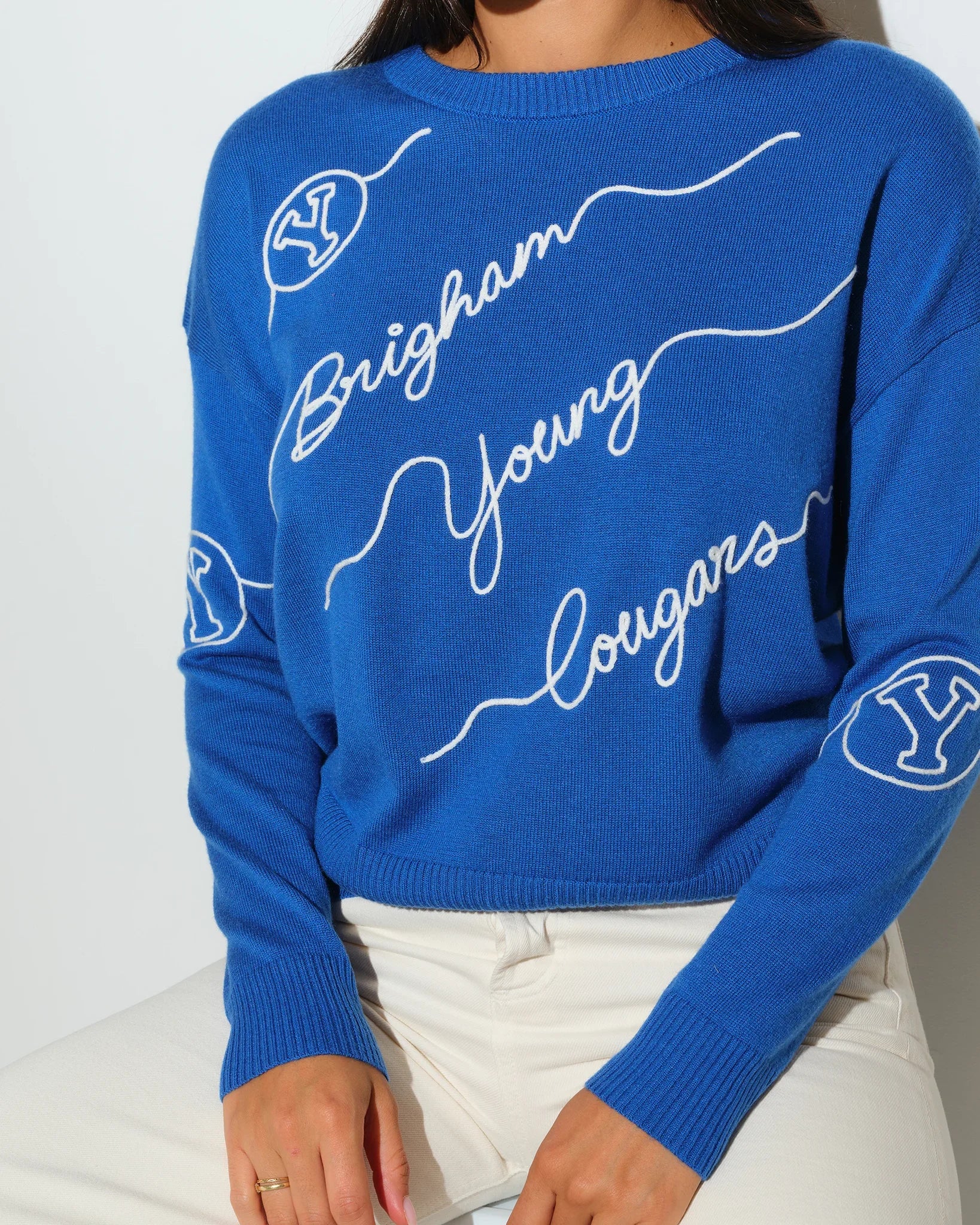 Royal blue BYU Cougars crewneck sweater featuring cursive "Brigham Young" script lettering across the front with a small BYU logo on the sleeve.