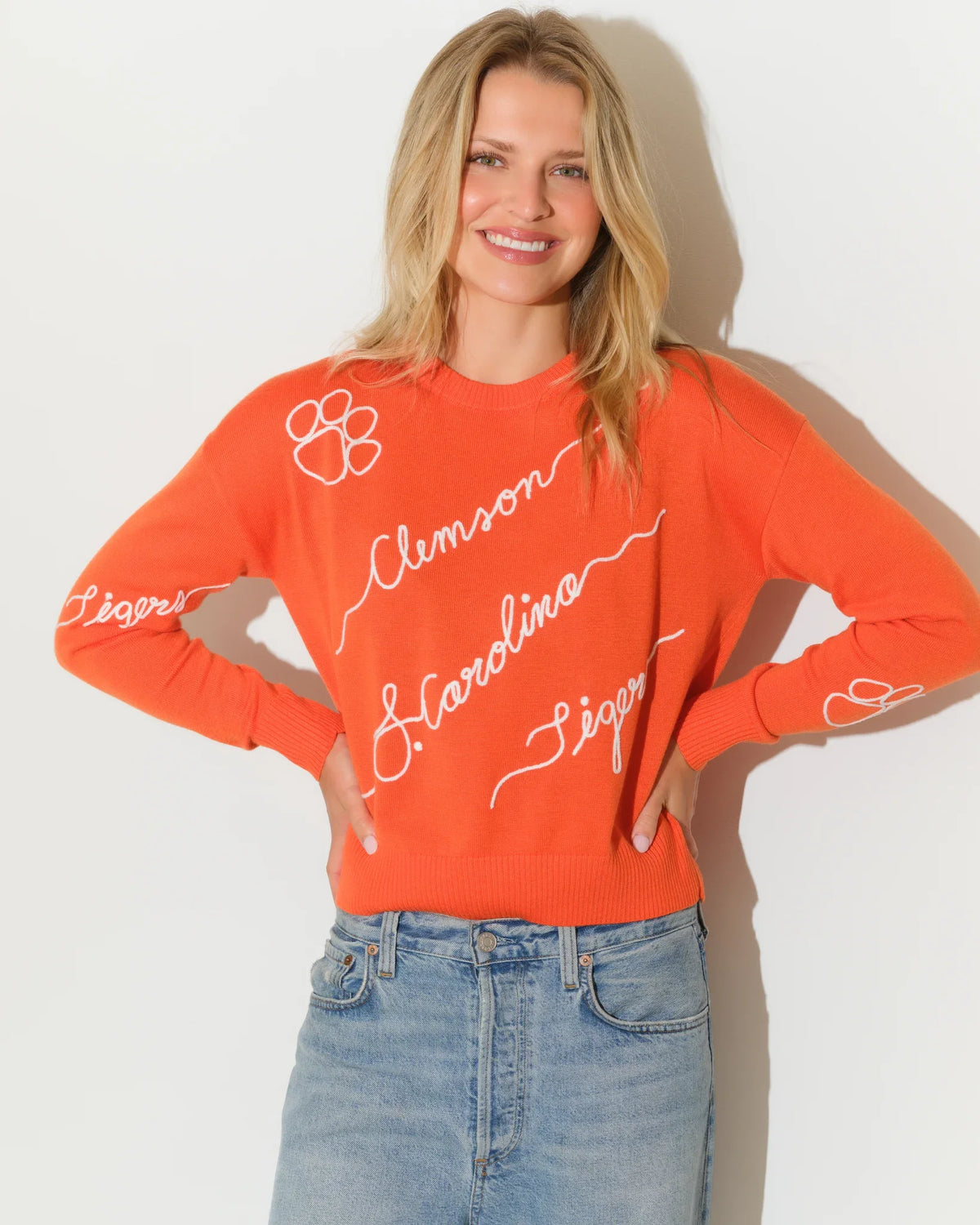 Orange Clemson Tigers Love Letter Sweater with cursive "Clemson," "Carolina," and "Tigers" script lettering and paw print details throughout.