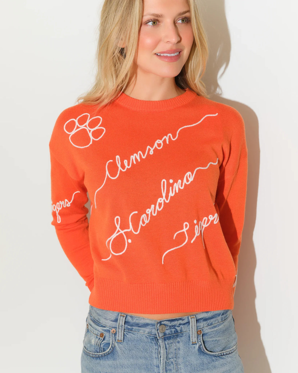 Orange Clemson Tigers Love Letter Sweater with cursive "Clemson," "Carolina," and "Tigers" script lettering and paw print details throughout.