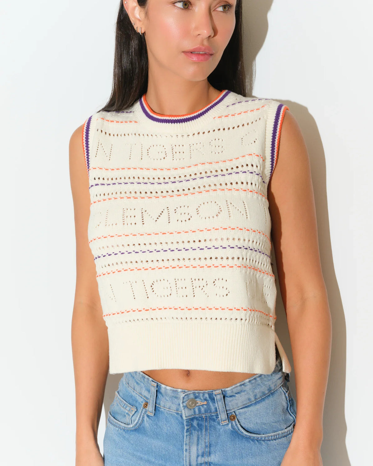 Ivory Clemson Tigers knit sweater vest with embroidered lettering, purple and orange trim at neckline, worn over jeans.