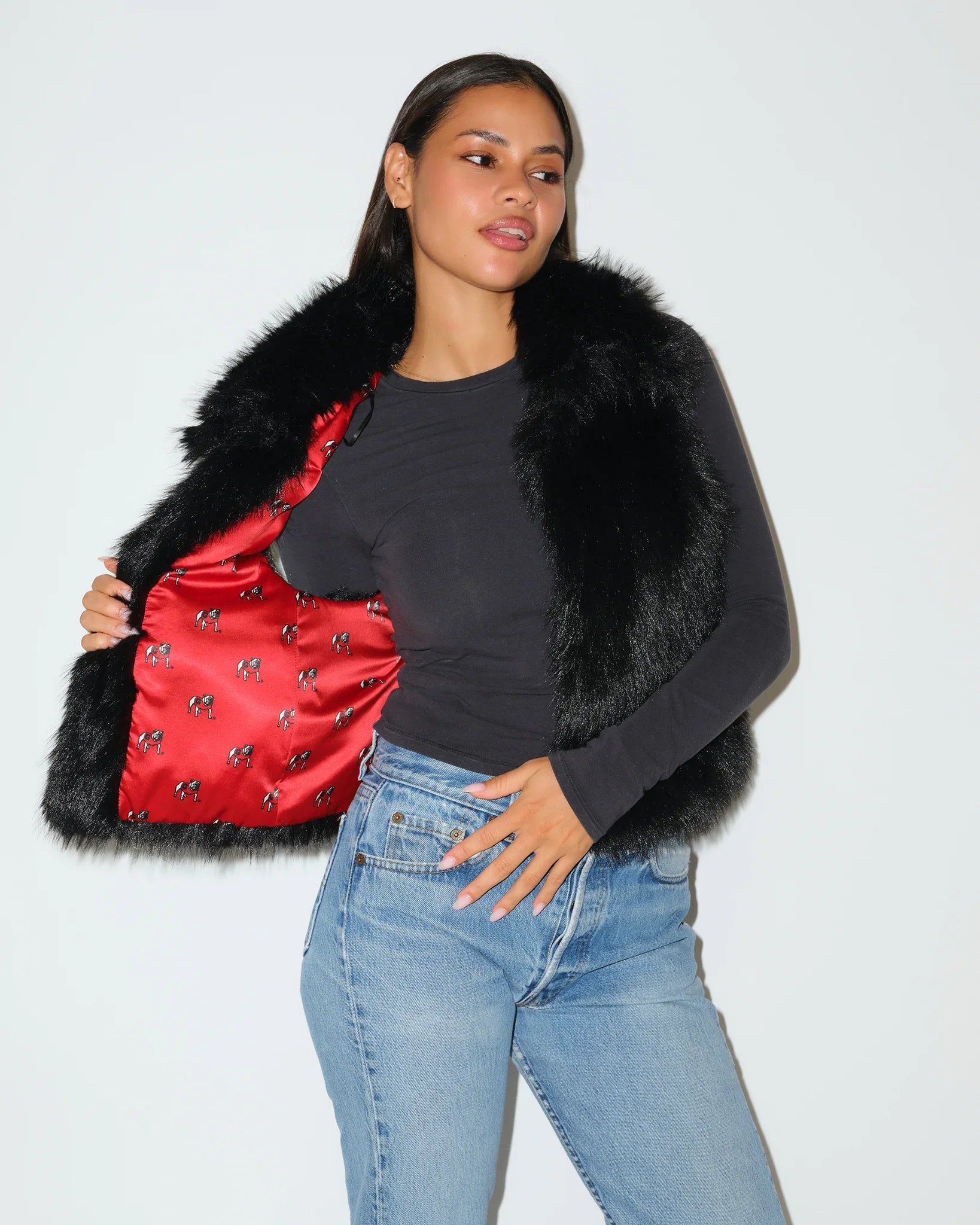 Black Georgia Bulldogs faux fur vest with fluffy texture and open front, styled over a gray long-sleeve top with jeans.