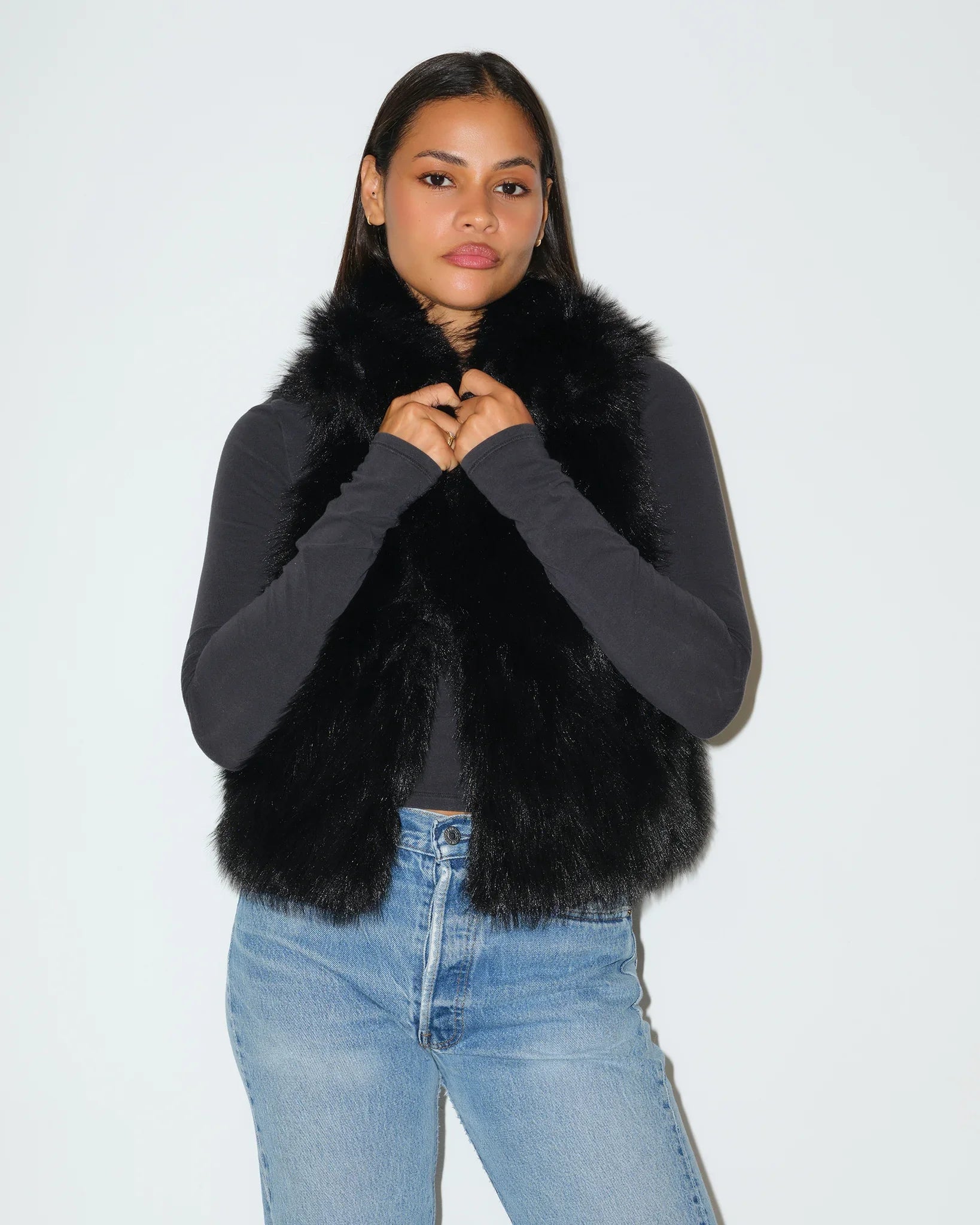 Black Georgia Bulldogs faux fur vest with fluffy texture and open front, styled over a gray long-sleeve top with jeans.