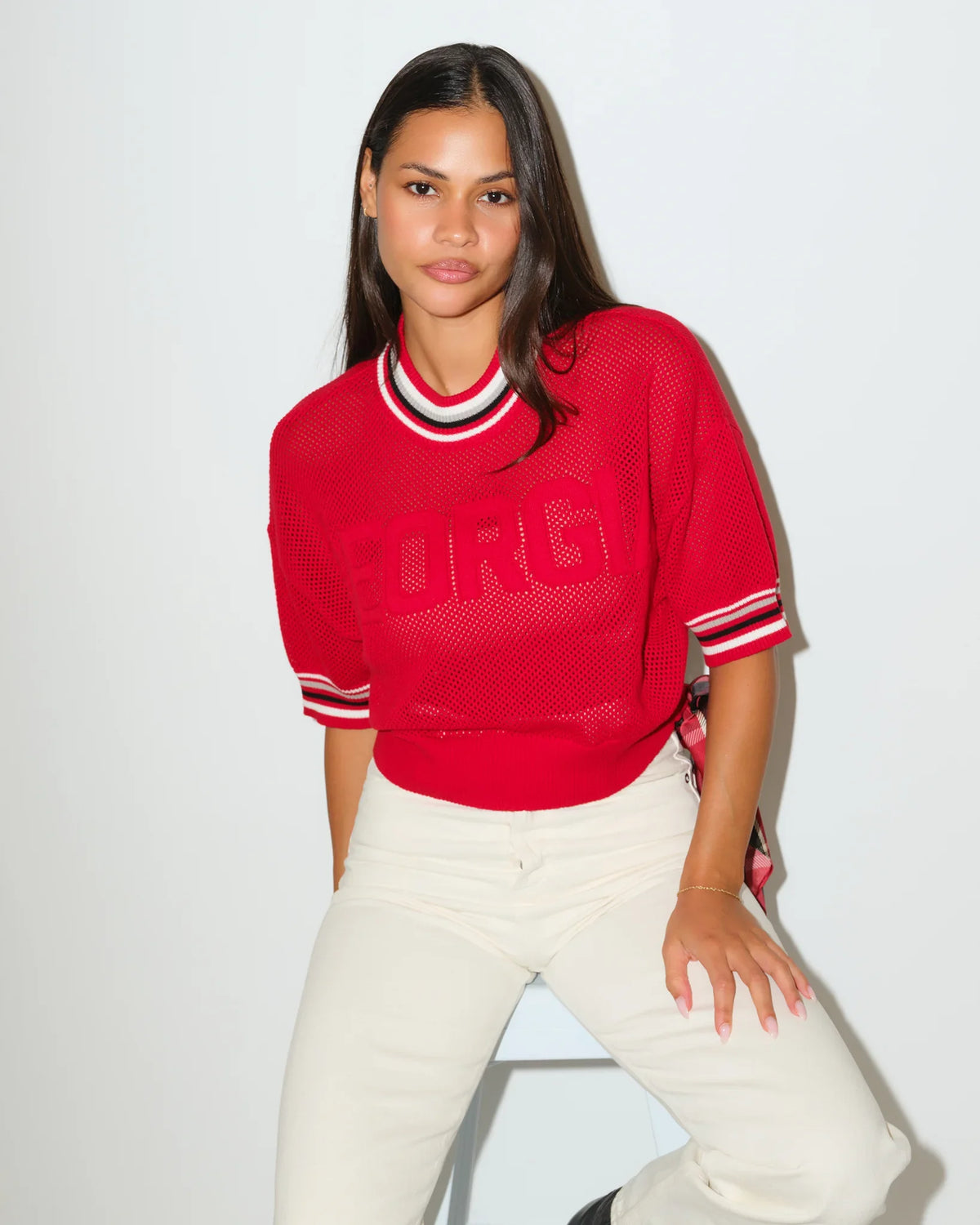 Red Georgia Bulldogs summer sweater with embossed lettering, striped ribbed collar, and short sleeves, styled with white pants.
