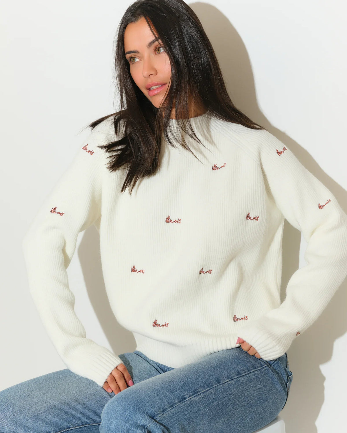 Ivory Illinois Fighting Illini fisherman sweater with allover embroidered script logos, worn with jeans.
