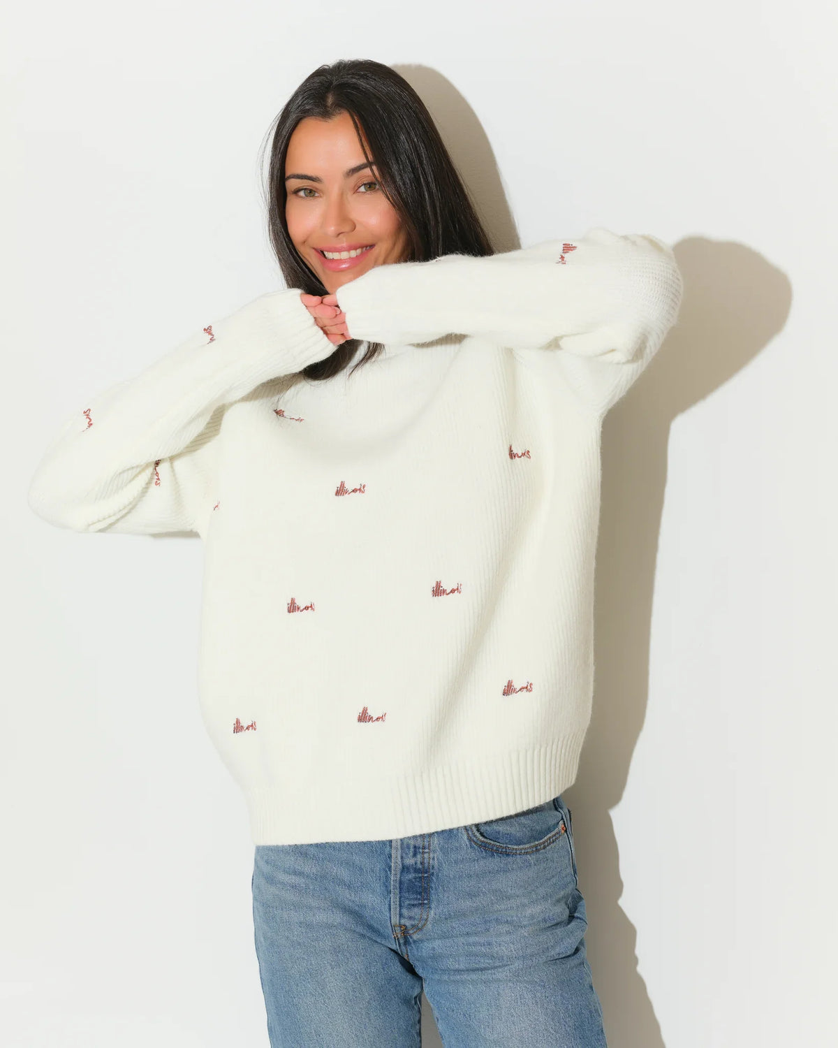 Ivory Illinois Fighting Illini fisherman sweater with allover embroidered script logos, worn with jeans.