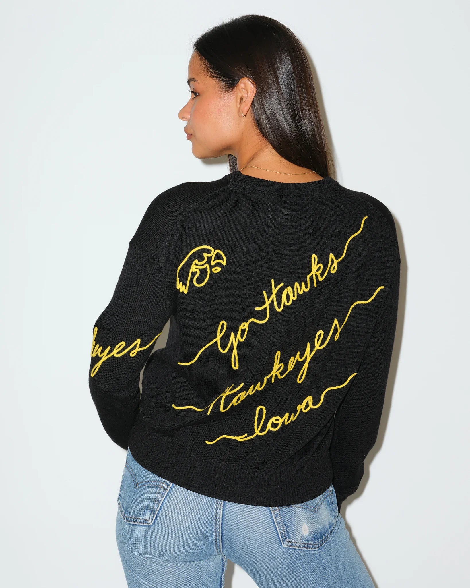 Black Iowa Hawkeyes crewneck sweater featuring gold script "Hawkeyes," "Iowa," and "Go Hawks" lettering with decorative accents throughout.
