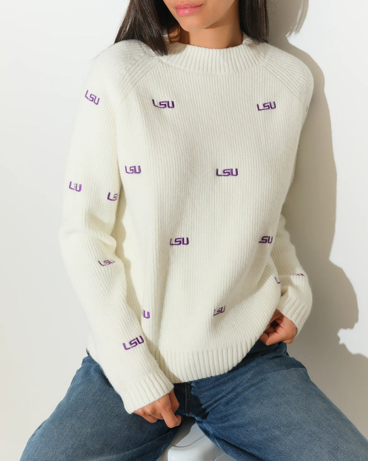 Ivory LSU Tigers fisherman sweater featuring repeated purple "LSU" embroidery throughout, shown on a model with a relaxed crewneck fit.