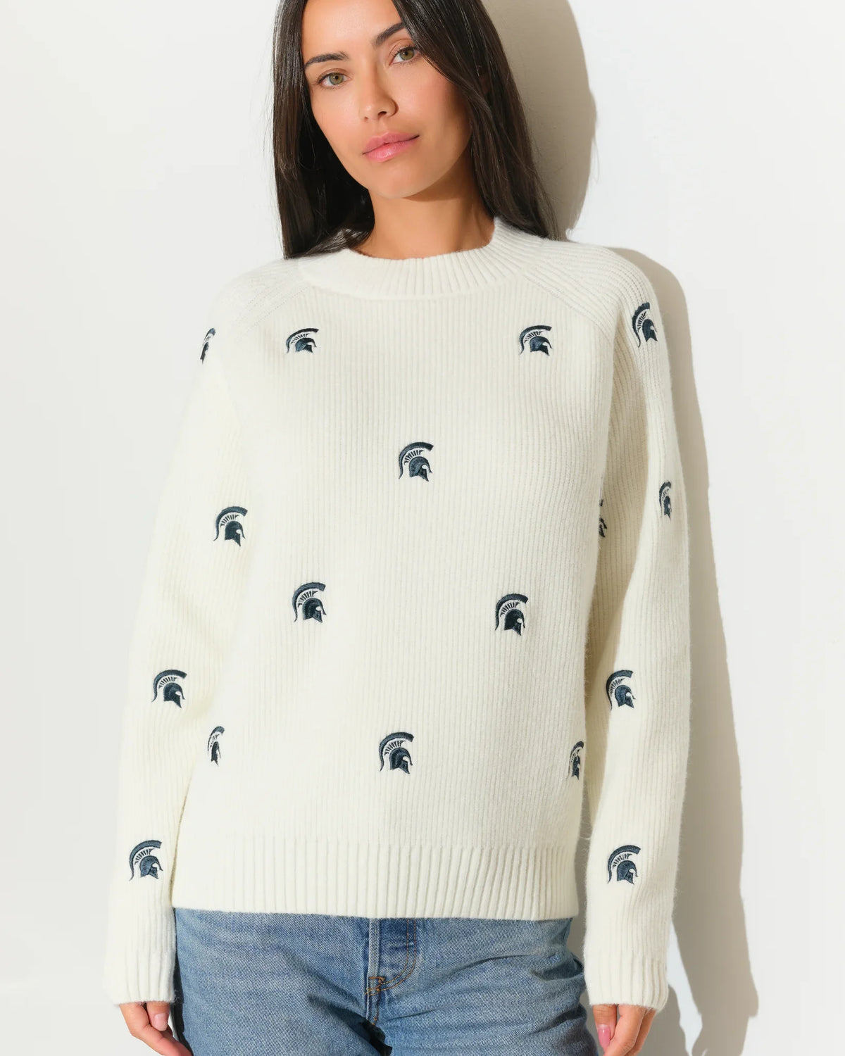 Ivory chunky knit Michigan State Spartans fisherman sweater with allover embroidered Spartan helmet logos, shown with a relaxed crew neck and long sleeves.