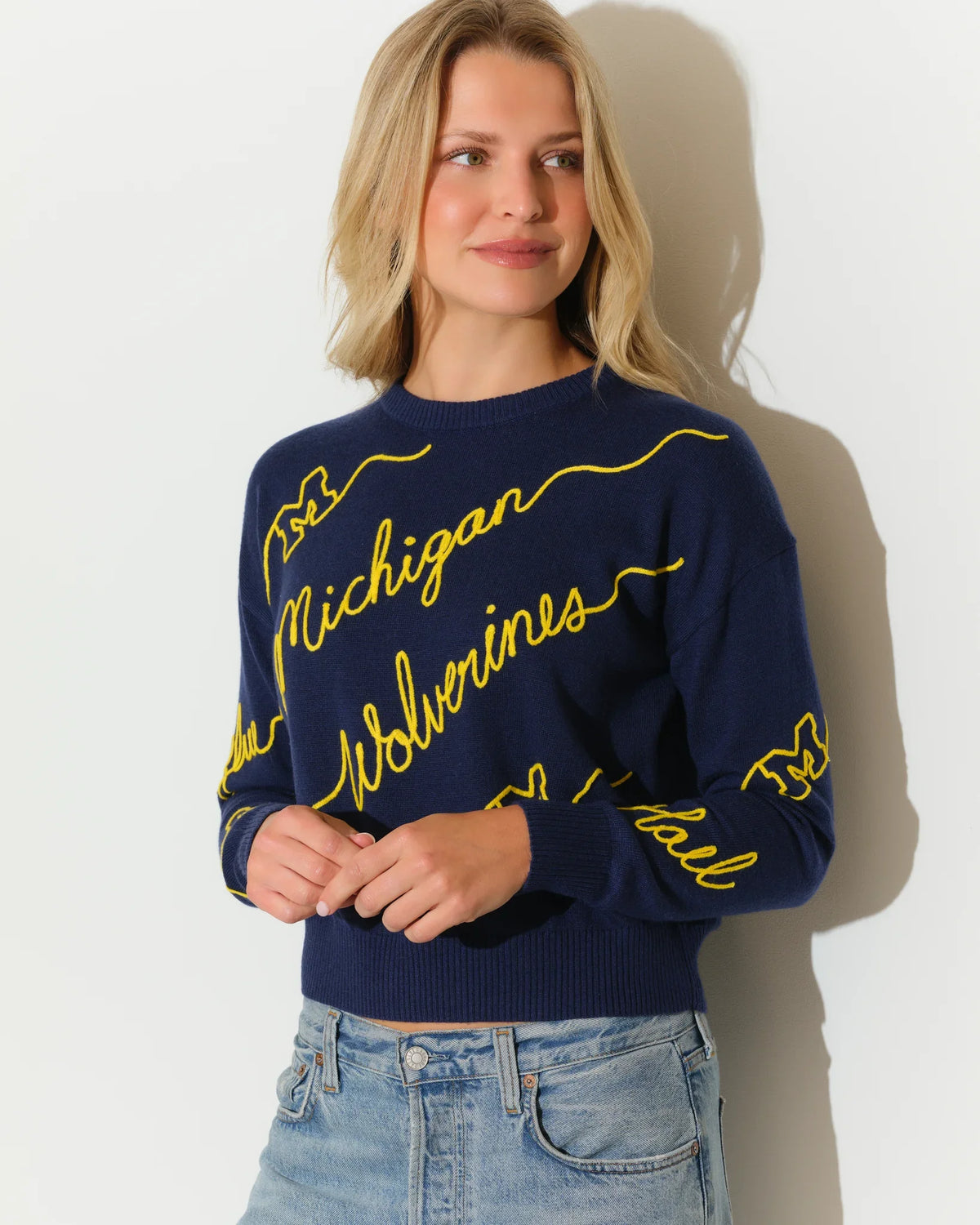 Navy Michigan Wolverines crew neck sweater with bold yellow cursive "Michigan Wolverines" script across the front and sleeves.