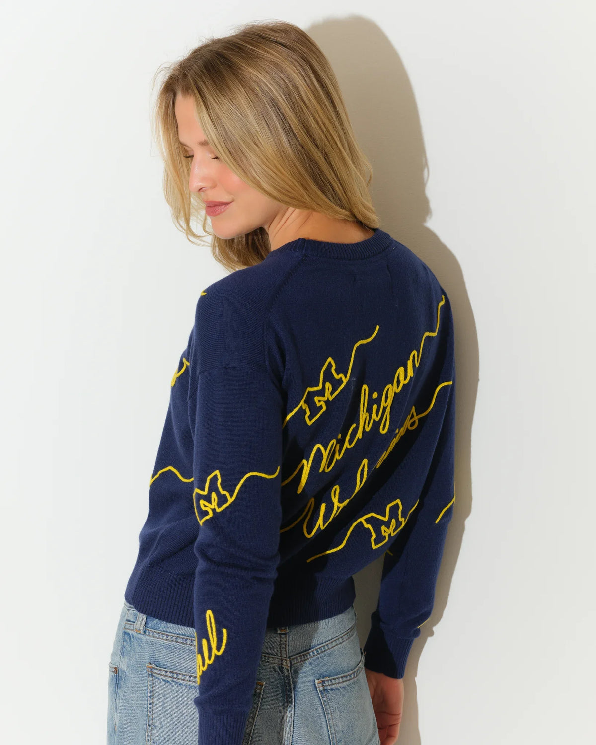 Navy Michigan Wolverines crew neck sweater with bold yellow cursive "Michigan Wolverines" script across the front and sleeves.