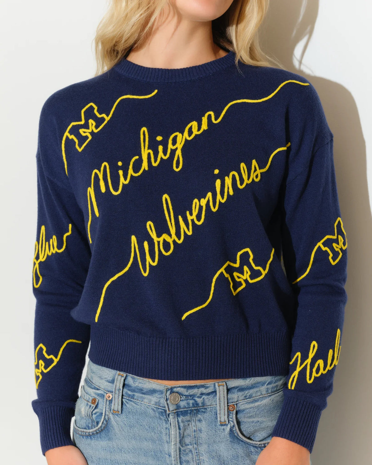Navy Michigan Wolverines crew neck sweater with bold yellow cursive "Michigan Wolverines" script across the front and sleeves.