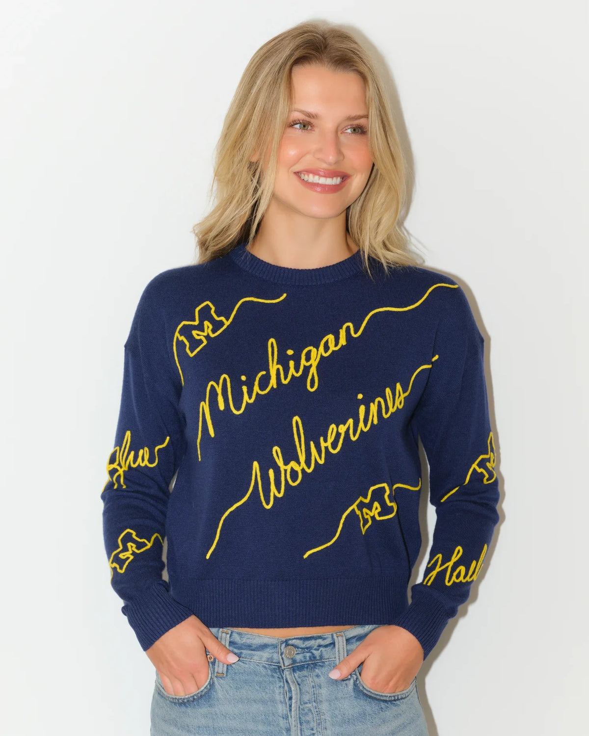 Navy Michigan Wolverines crew neck sweater with bold yellow cursive "Michigan Wolverines" script across the front and sleeves.