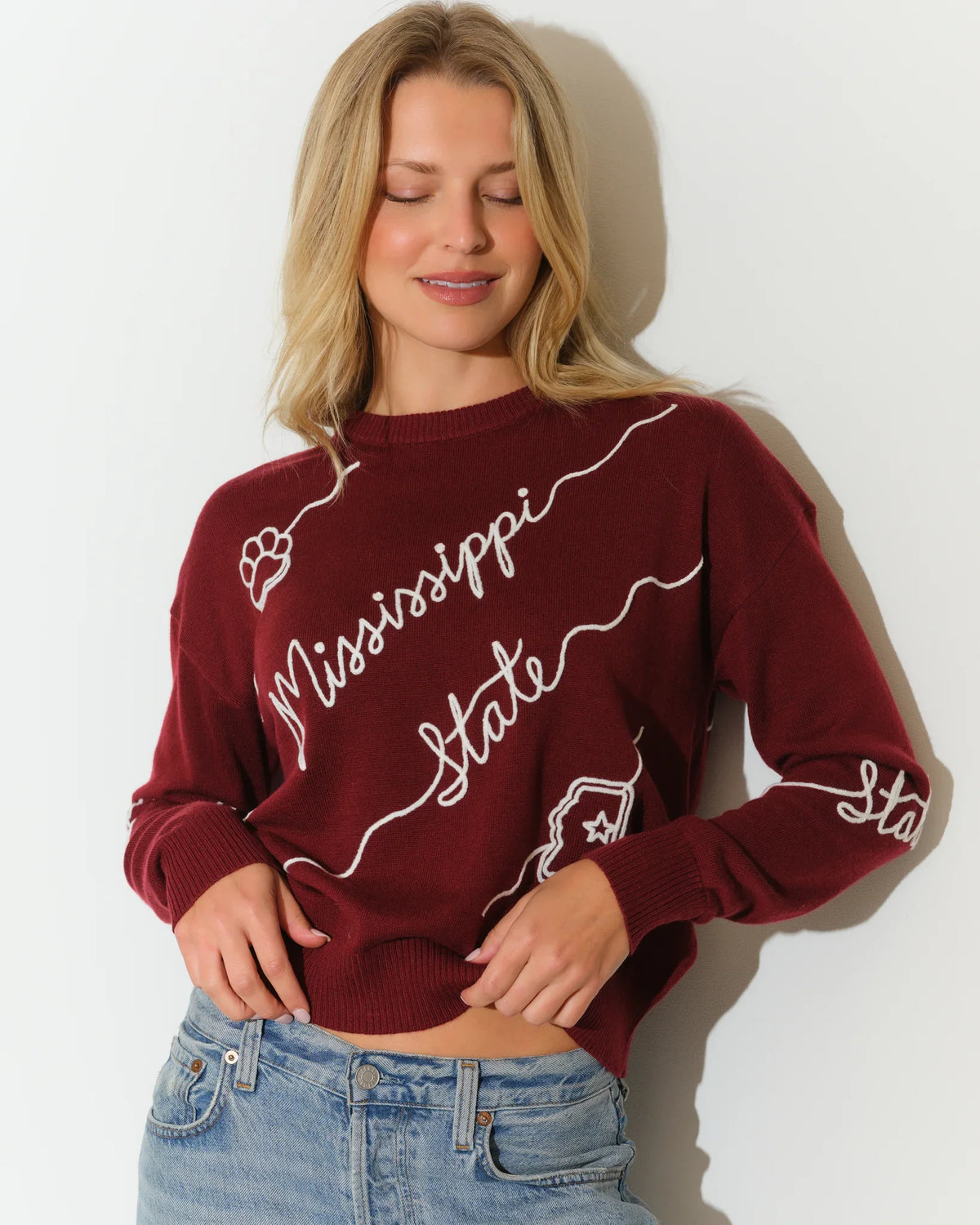 Maroon Mississippi State Bulldogs crew neck sweater with white cursive "Mississippi State" script and decorative wave detailing across the front.