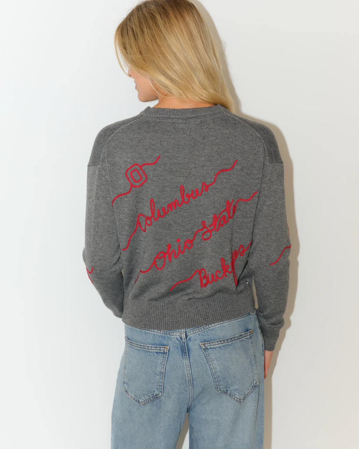 Gray Ohio State Buckeyes cropped knit sweater with red cursive script lettering across the front, styled with light wash denim.