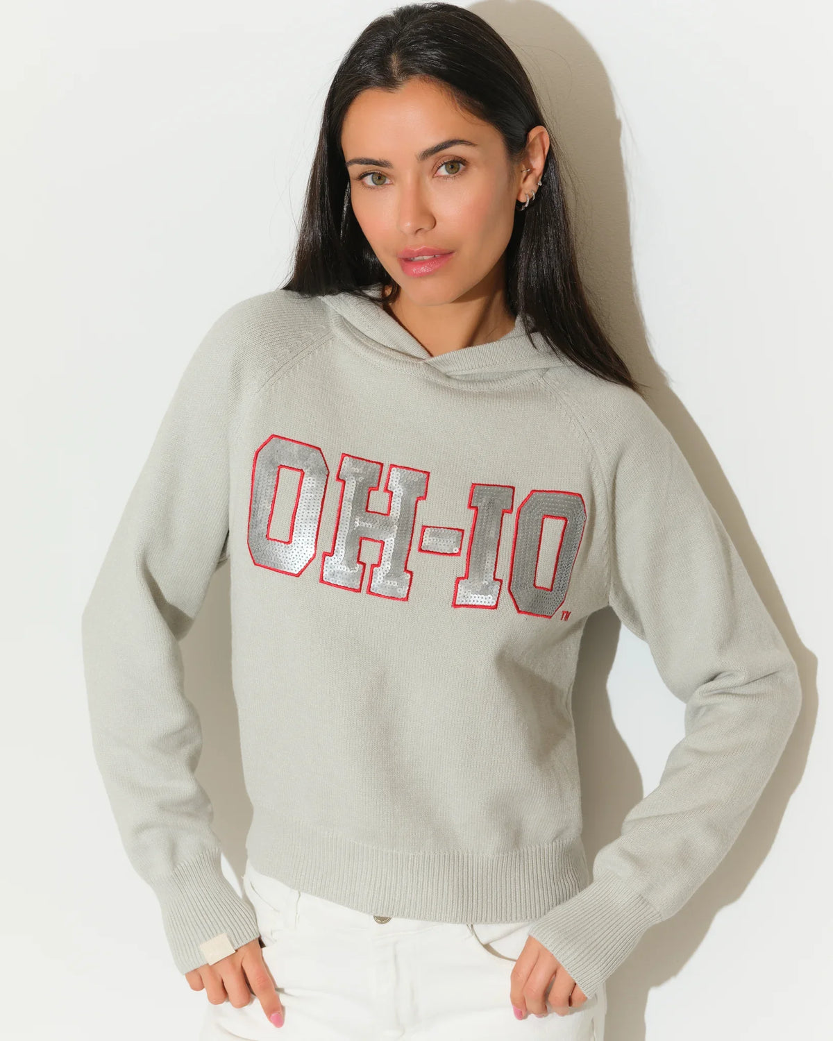 Gray Ohio State Buckeyes sequin knit hoodie with bold "OH-IO" lettering in red and gray on the chest, worn by a woman.