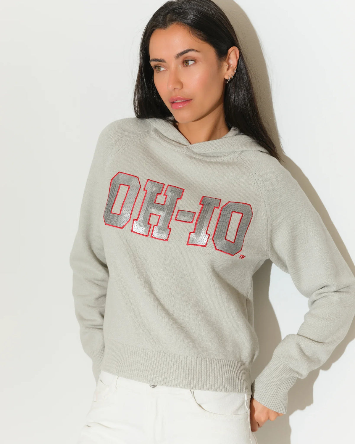 Gray Ohio State Buckeyes sequin knit hoodie with bold "OH-IO" lettering in red and gray on the chest, worn by a woman.