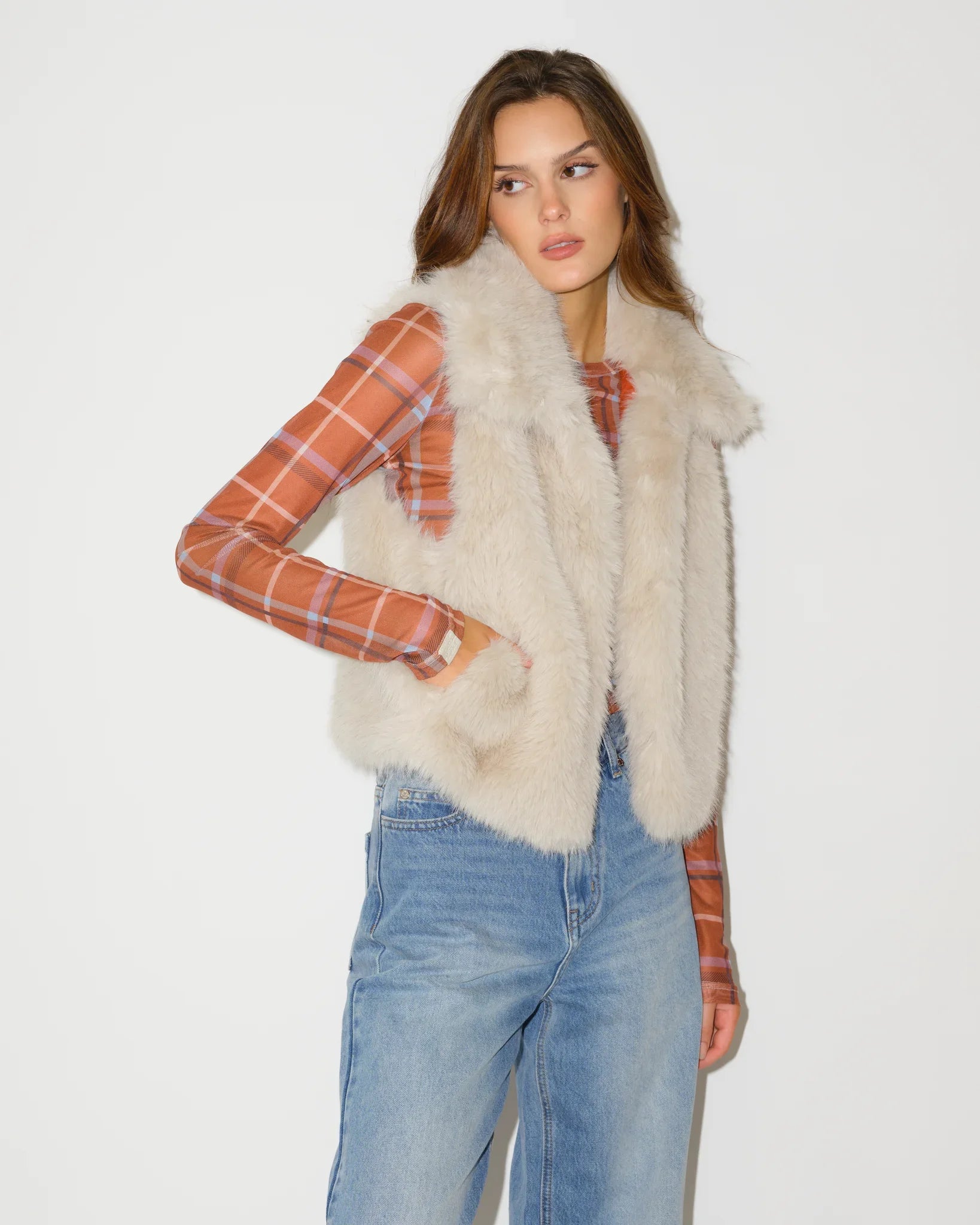 Ivory faux fur Texas Longhorns vest shown open, revealing an orange plaid lining with Longhorns logo print, paired with jeans.