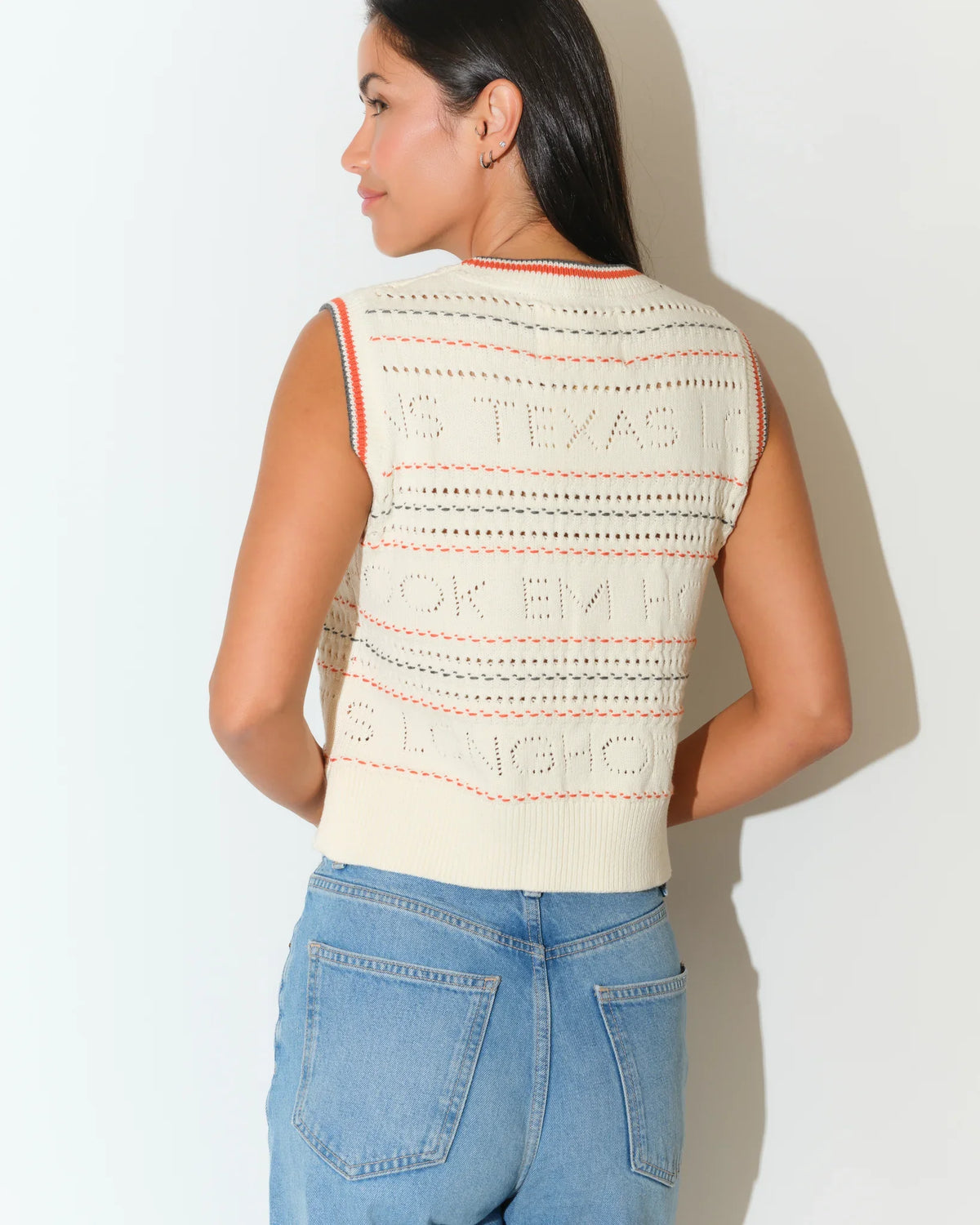 Ivory Texas Longhorns knit sweater vest with textured pattern and striped neckline, styled casually with jeans.