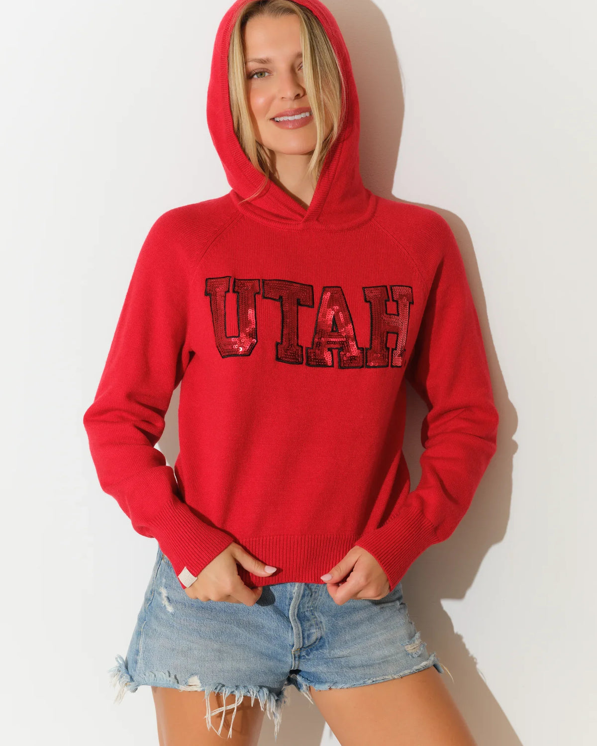 Red Utah Utes women's cropped pullover hoodie featuring sequin block letter "UTAH" graphic across the chest.