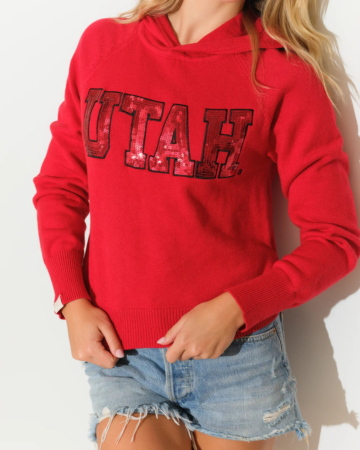 Red Utah Utes women's cropped pullover hoodie featuring sequin block letter "UTAH" graphic across the chest.