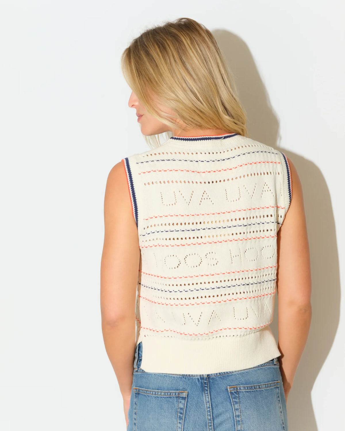 Ivory Virginia Cavaliers pointelle knit sweater vest with embroidered team lettering, navy trim at neckline, styled with blue jeans.