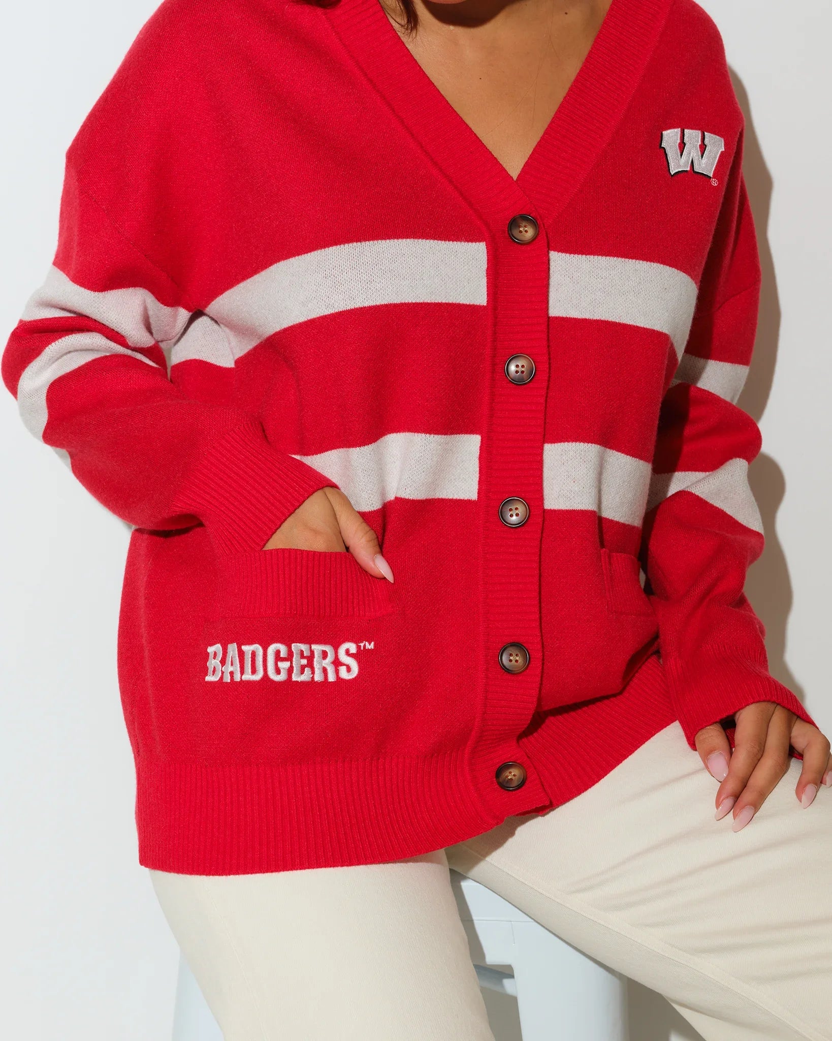 Red Wisconsin Badgers Vinti cardigan with white chest stripes, V-neck, button front, and embroidered "W" logo on the left chest.