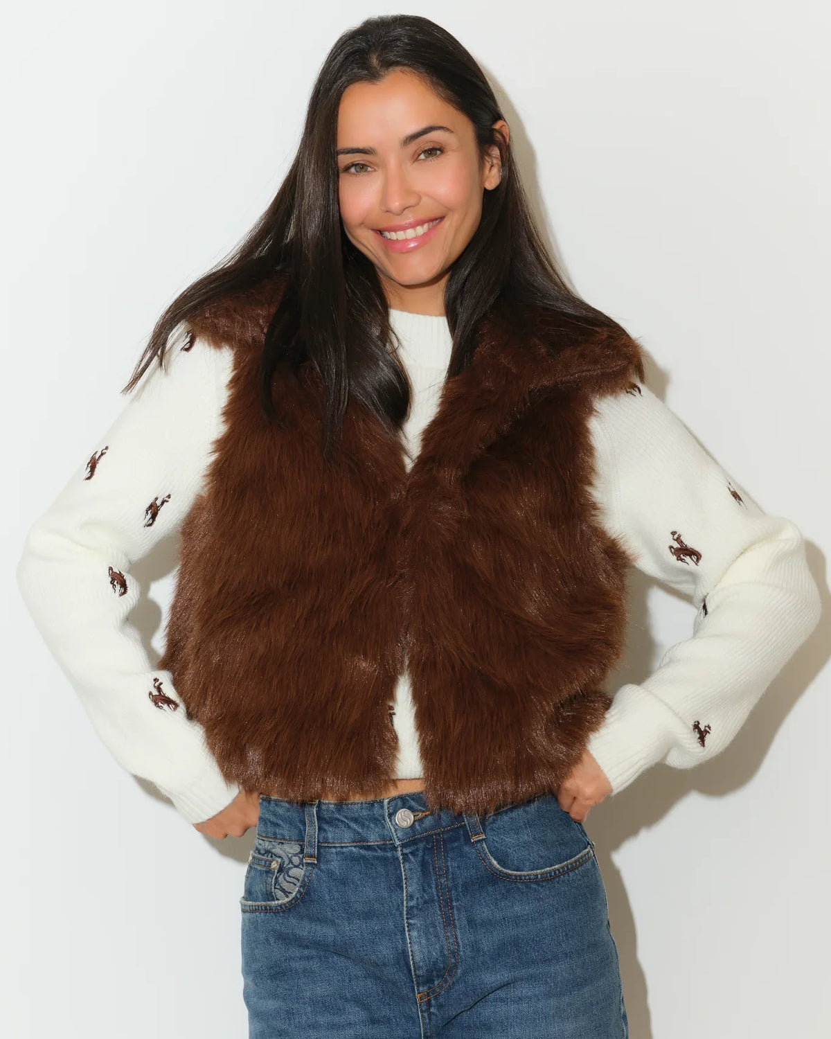 Brown faux fur Wyoming Cowboys vest with gold printed lining, shown open over a white Cowboys-embroidered sweater.